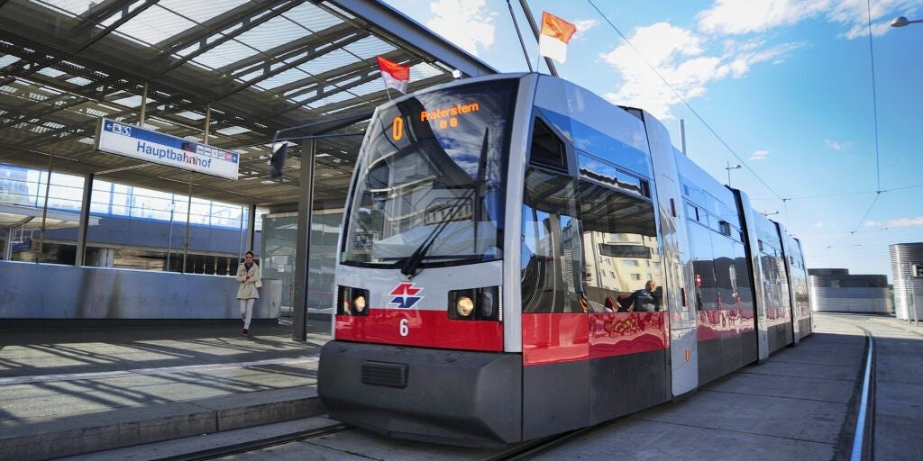 Straßenbahn an einer Haltestelle mit dem Schild "Hauptbahnhof" in Wien bei sonnigem Wetter.