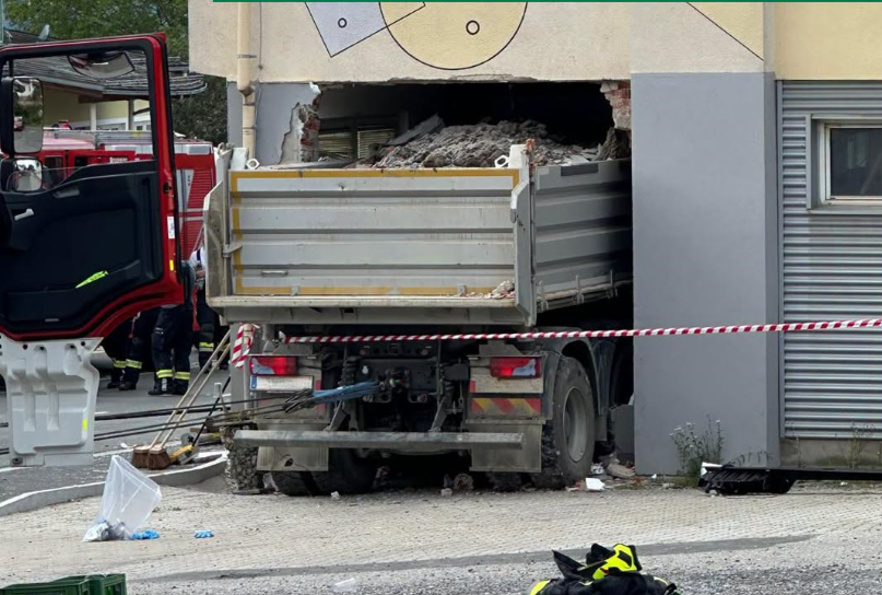 Ein Schotter-Lkw ist in ein Geschäft gefahren, die Fassade ist stark beschädigt.