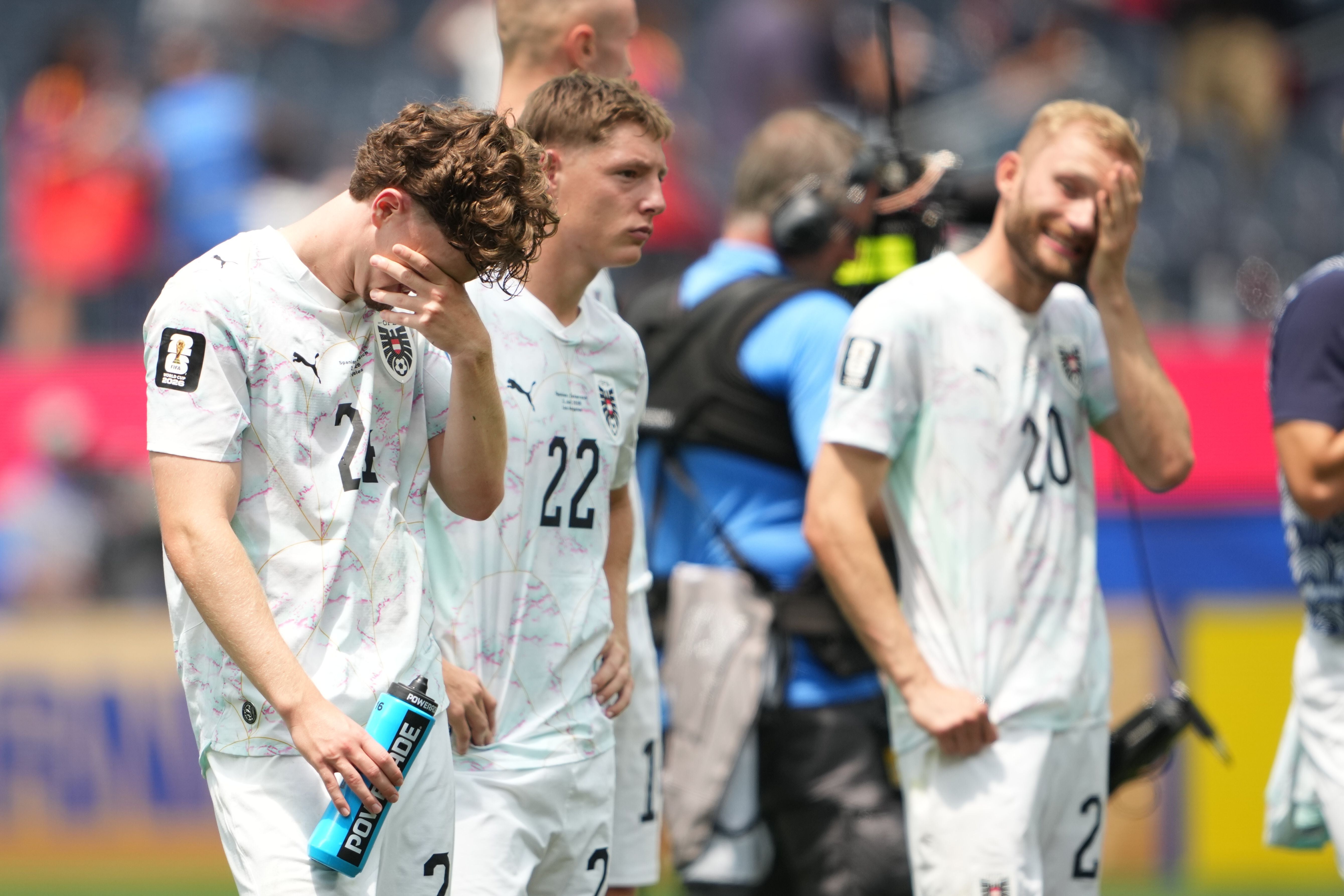 Drei enttäuschte österreichische Fußballspieler stehen nach einem Spiel auf dem Feld.