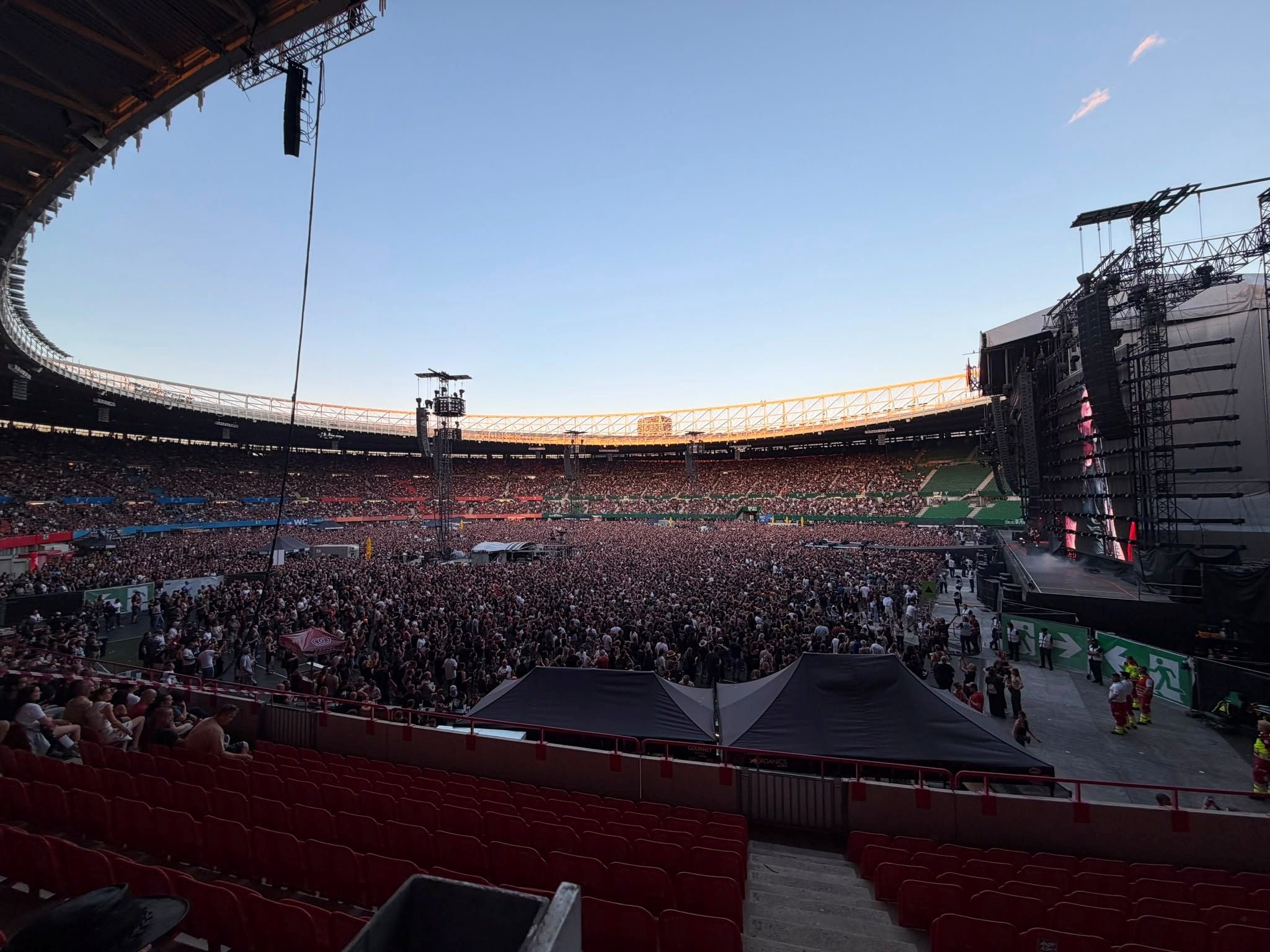 Großes Stadionkonzert der Foo Fighters mit Menschenmenge vor der Bühne bei Sonnenuntergang.