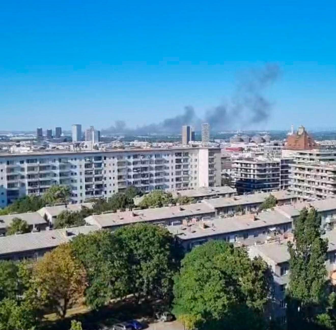 Blick über Wohnhäuser in Stadlau, im Hintergrund steigt schwarzer Rauch in den Himmel.