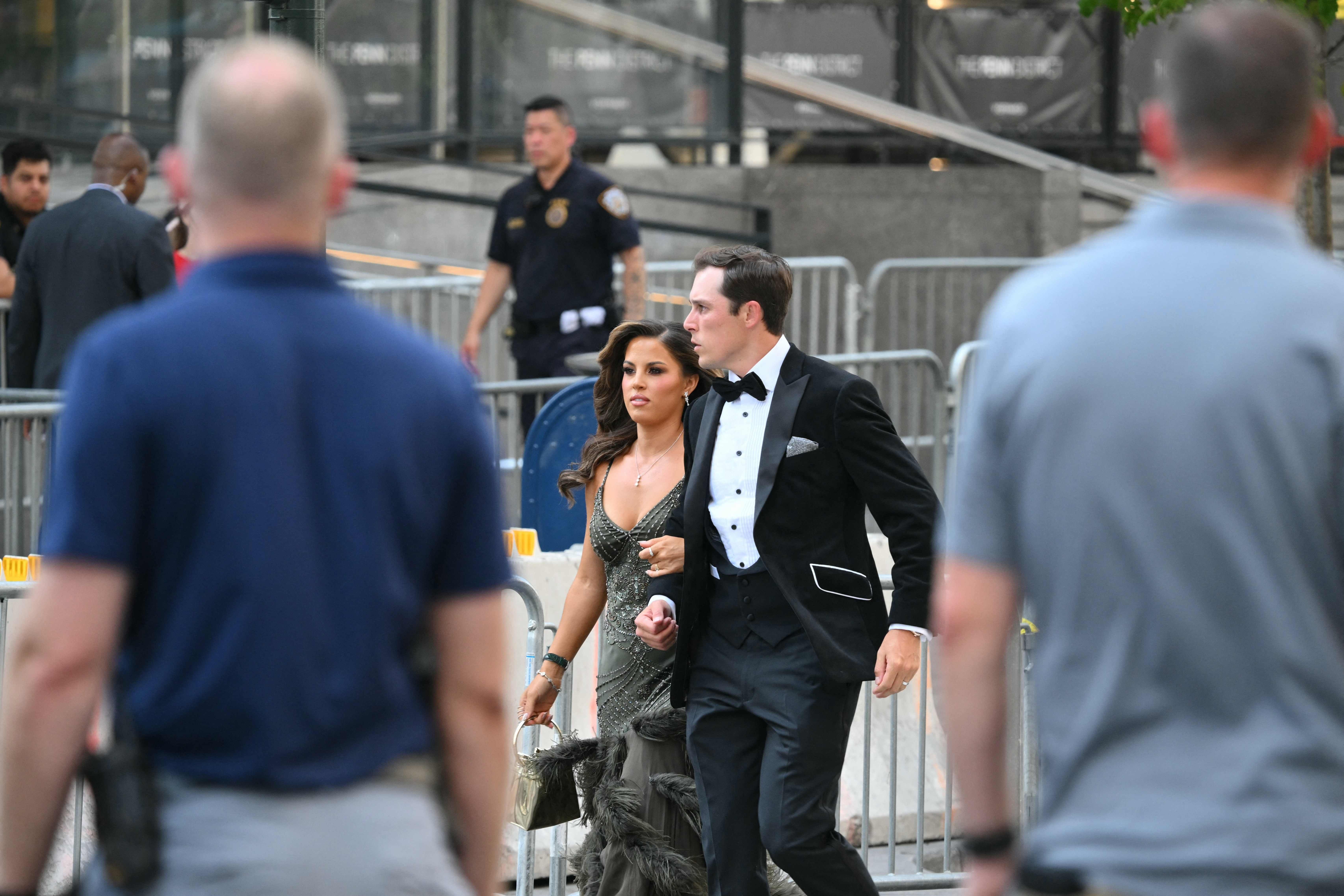 Ein elegant gekleidetes Paar geht an Sicherheitsabsperrungen und Polizei vor Madison Square Garden vorbei.