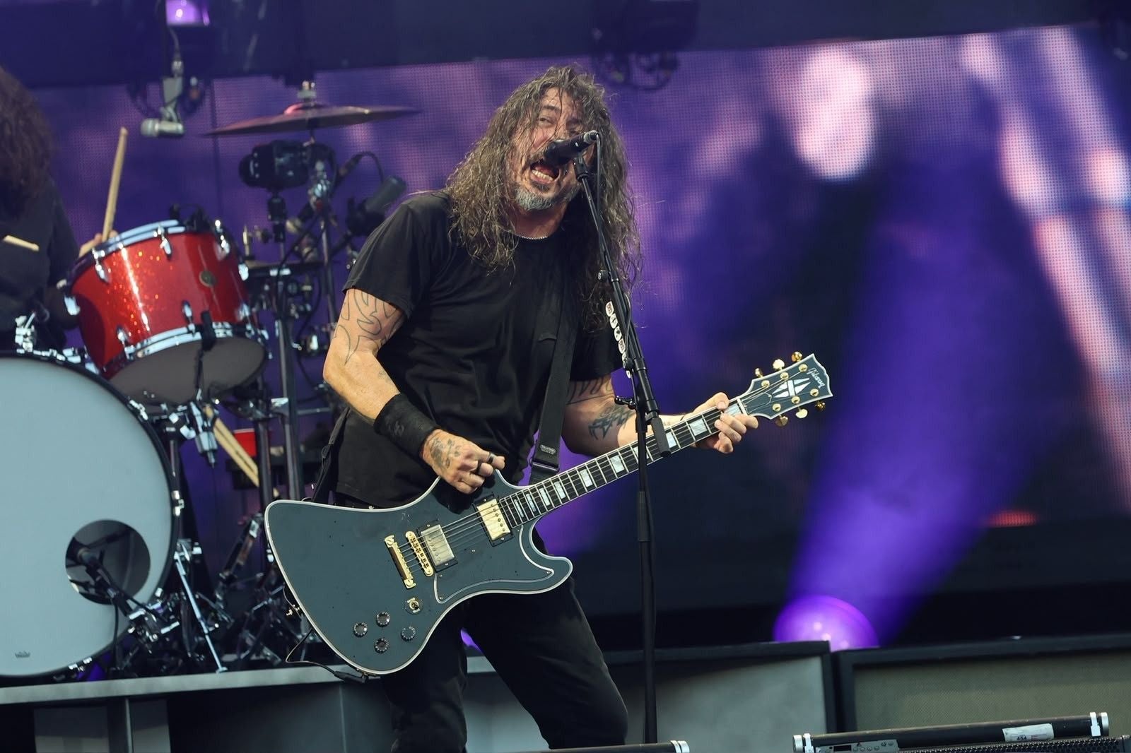 Ein Musiker der Foo Fighters spielt Gitarre und singt auf einer Konzertbühne.