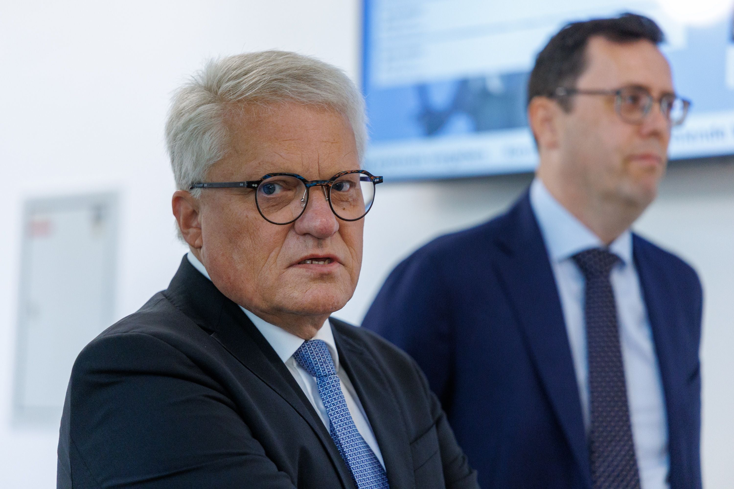 Zwei Männer im Anzug, einer im Vordergrund mit Brille, bei einem Gerichtstermin in Linz.