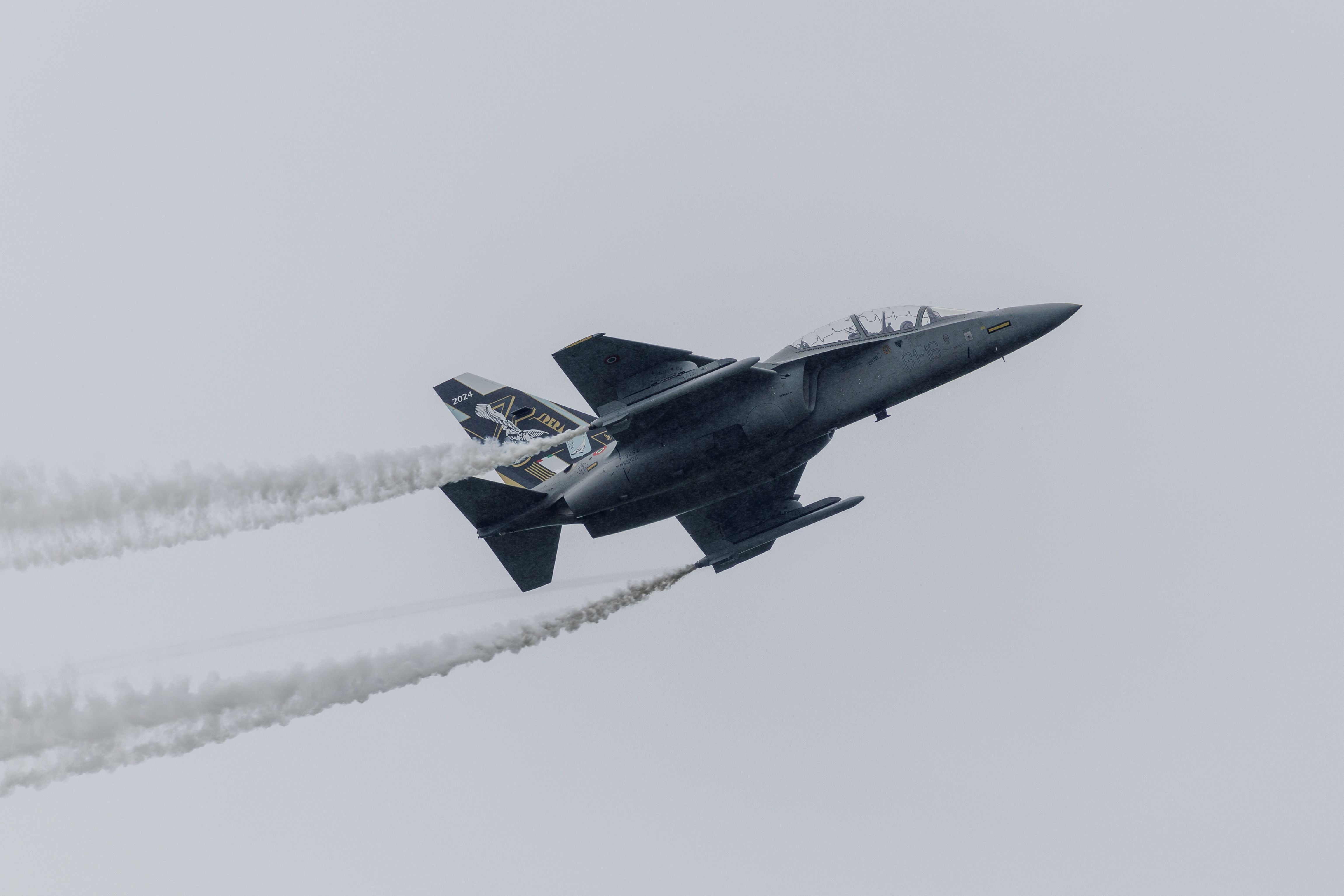 Ein Militärjet Aermacchi Alenia MA-346 fliegt mit Kondensstreifen am bewölkten Himmel.