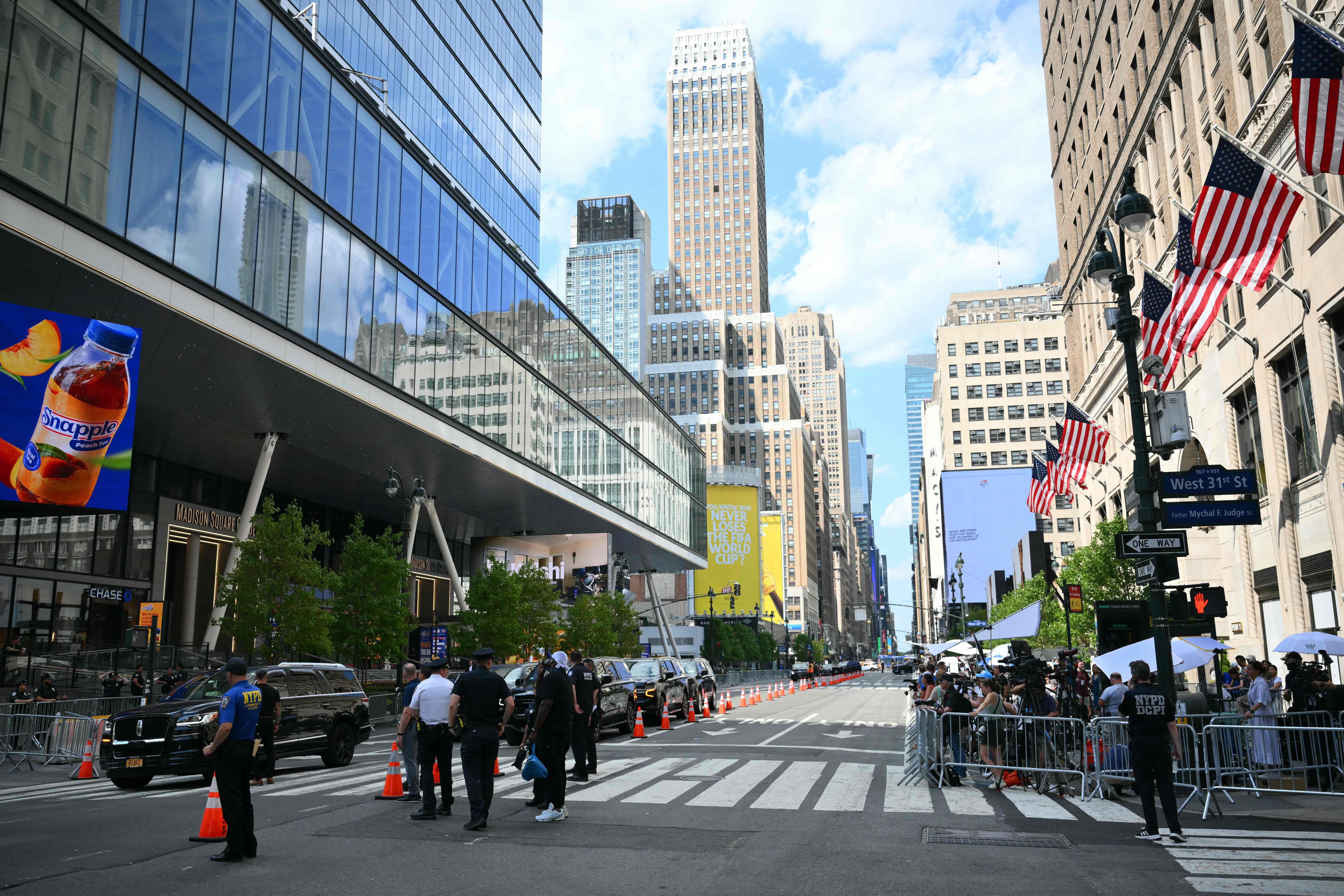 Straßenszene vor dem Madison Square Garden mit Polizeipräsenz, Medienvertretern und Absperrungen.