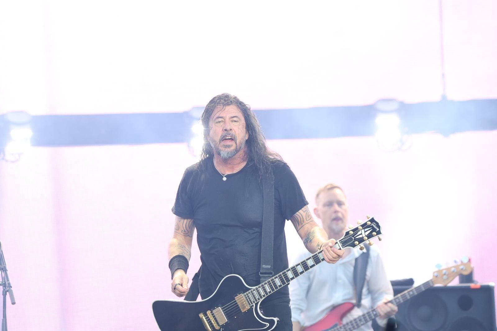 Ein Gitarrist der Foo Fighters spielt auf der Bühne vor hellem Hintergrund.