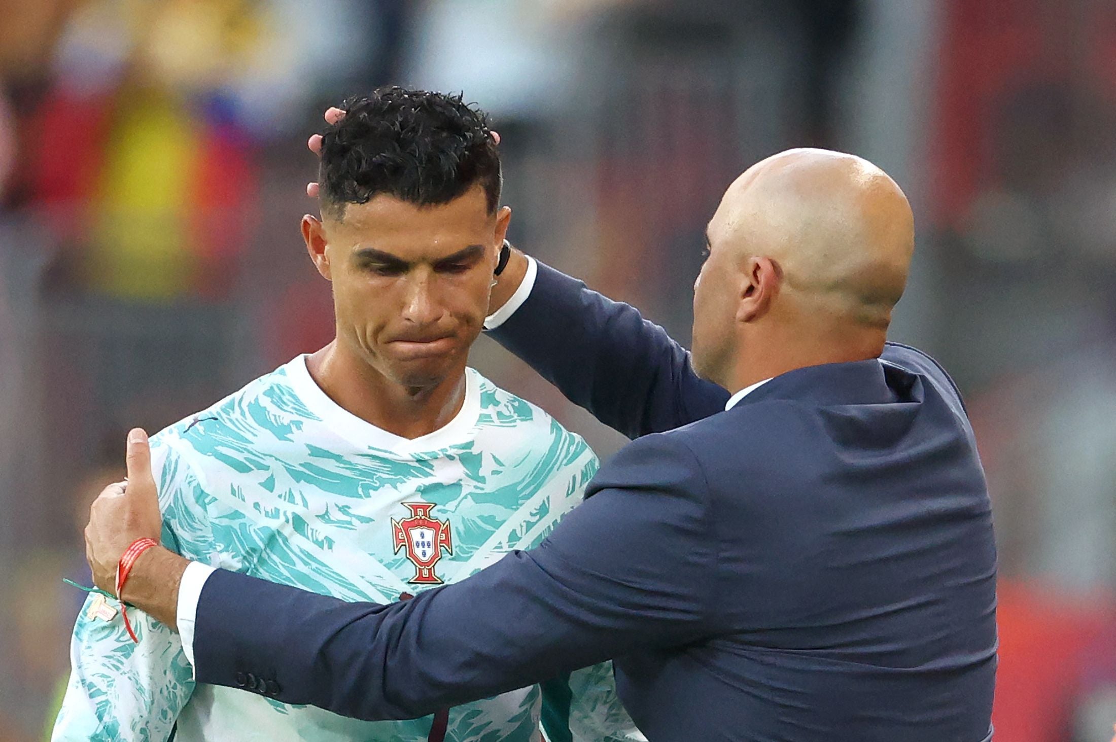 Ein Fußballspieler mit Portugal-Trikot wird vom Trainer am Kopf getröstet.