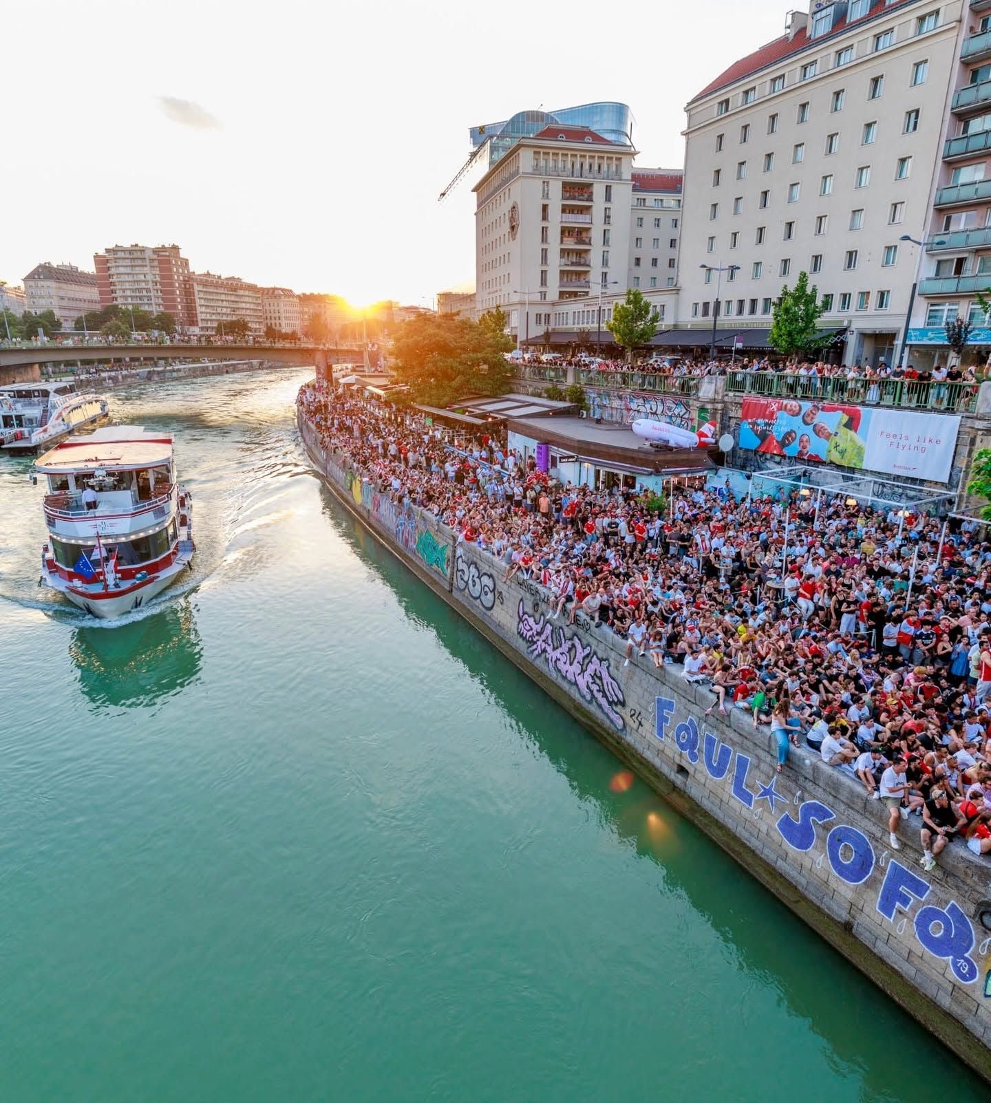Große Menschenmenge schaut beim Public Viewing am Donaukanal einem Schiff und der Leinwand zu.