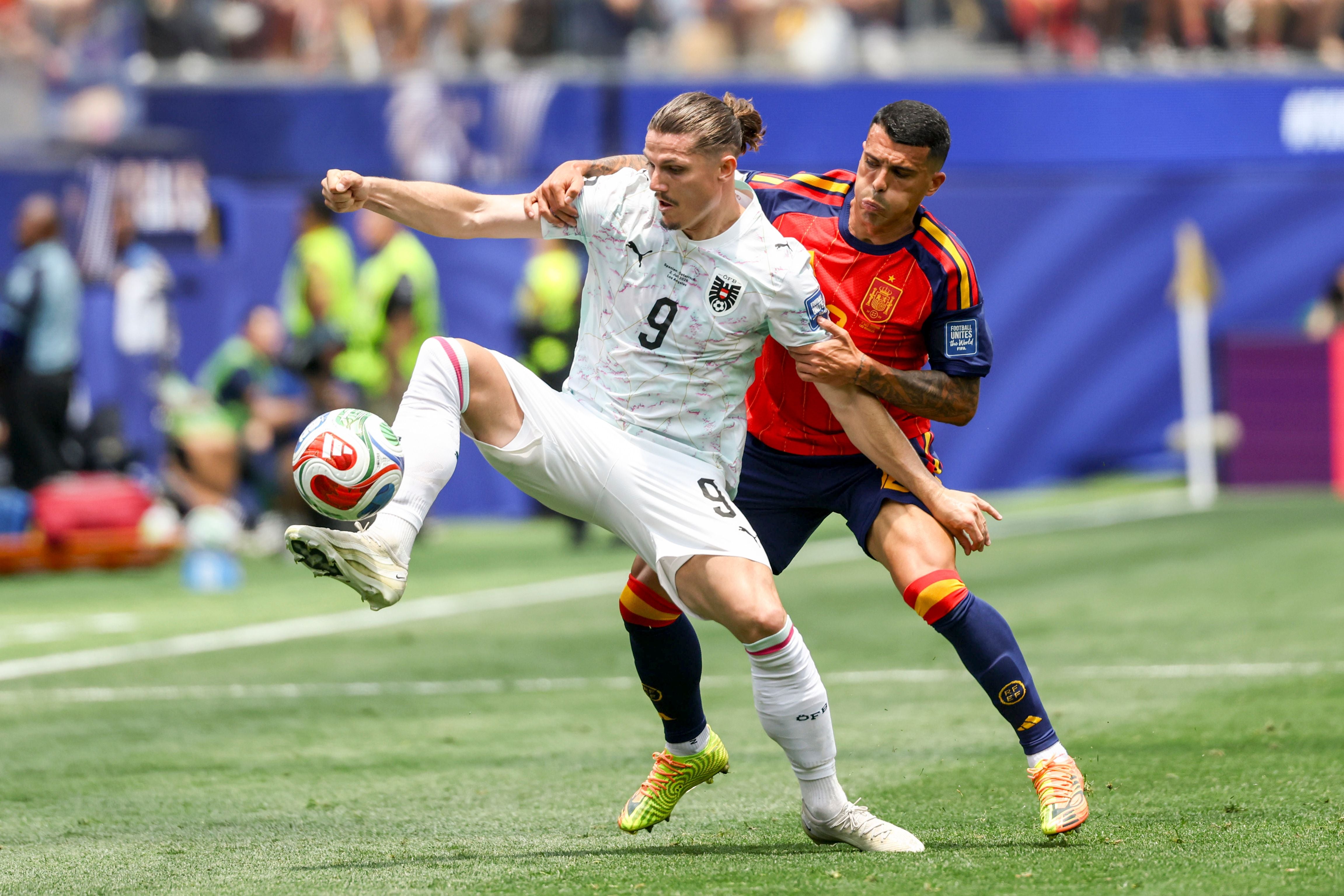 Zwei Fußballspieler aus Österreich und Spanien kämpfen um den Ball auf dem Spielfeld.