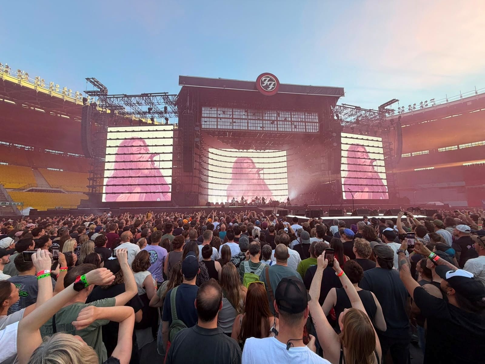 Große Menschenmenge bei einem Foo Fighters Konzert in einem Stadion mit Bühne und Großbildschirmen.