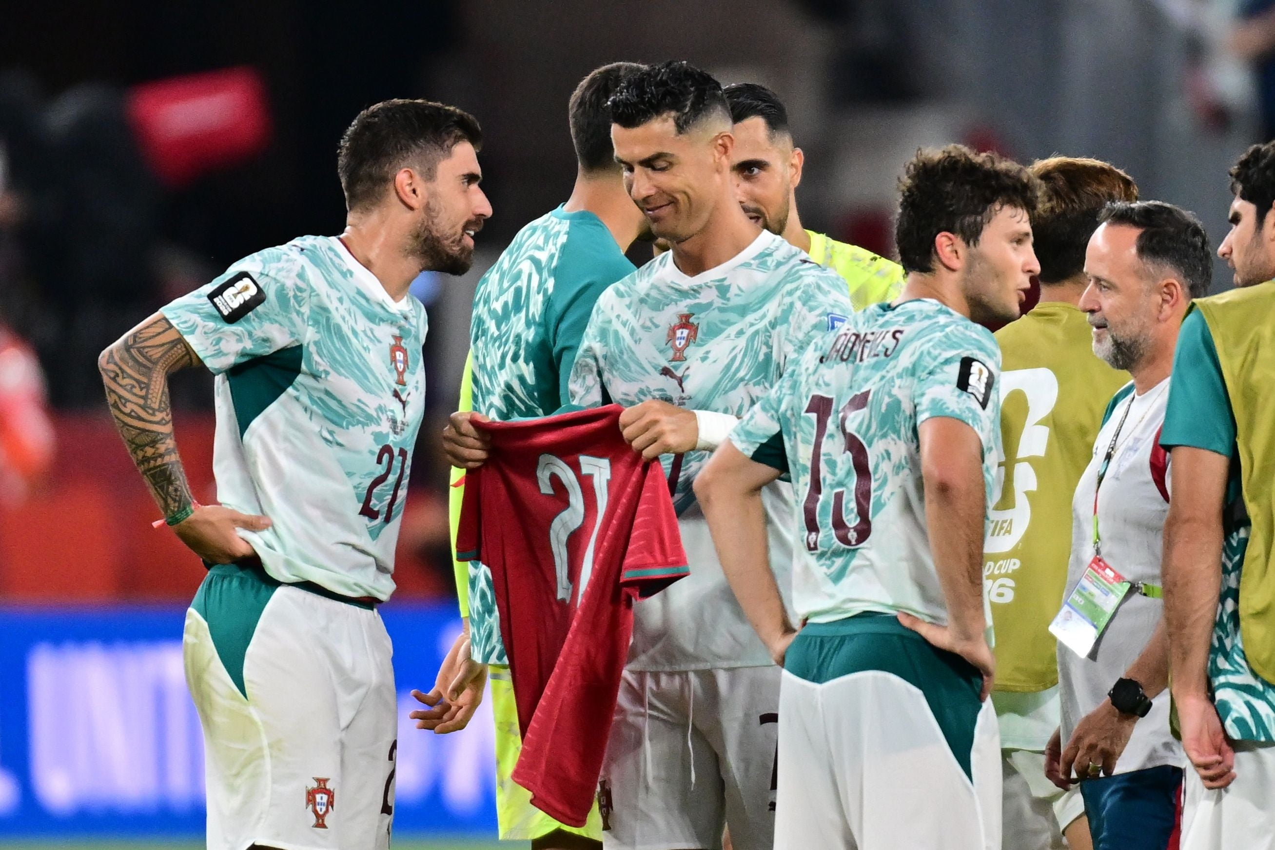 Portugiesische Fußballspieler feiern nach einem Sieg, ein Spieler hält ein Trikot mit der Nummer 21.