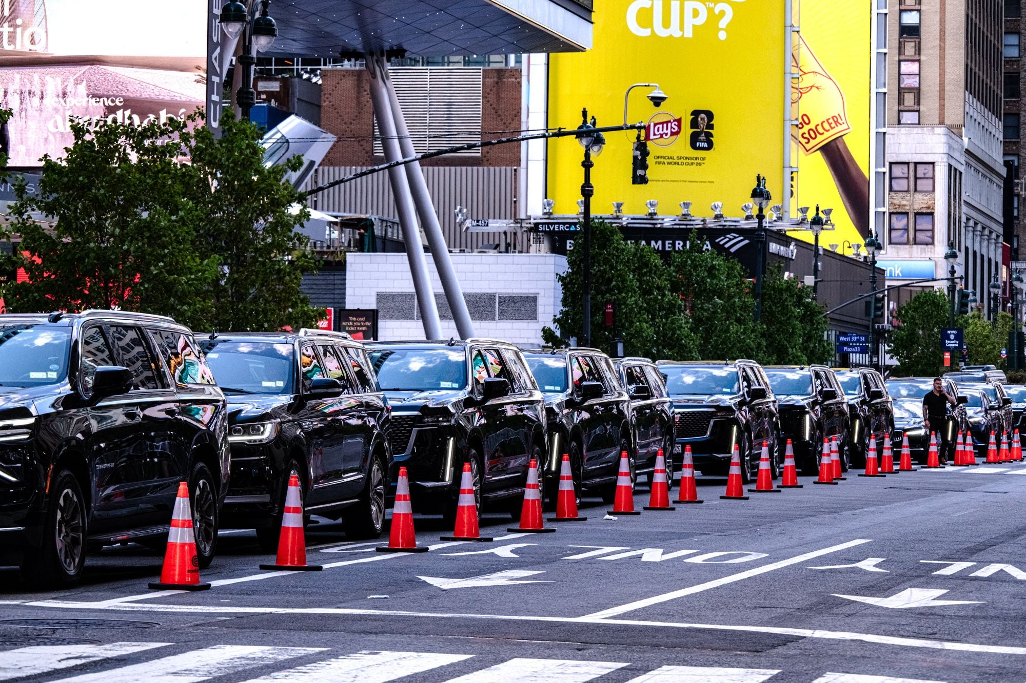 Eine lange Reihe schwarzer SUVs steht hinter Verkehrskegeln auf einer Straße in New York.