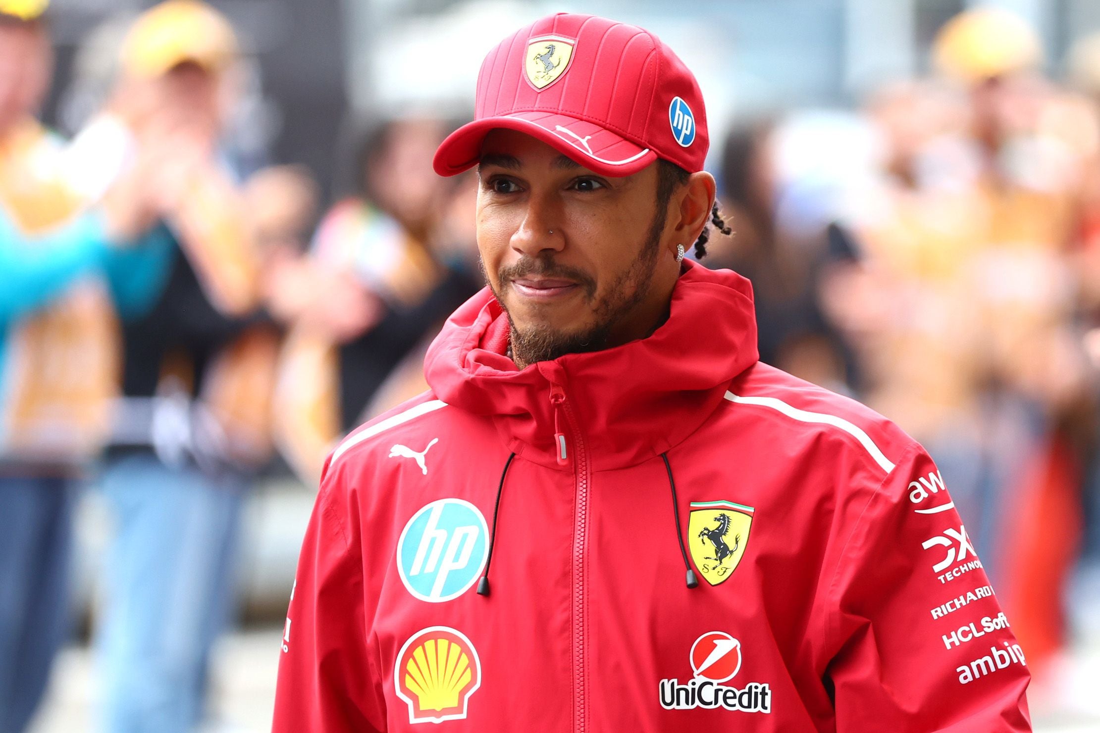 Ein Mann in roter Ferrari-Teamkleidung steht draußen und lächelt in die Kamera.