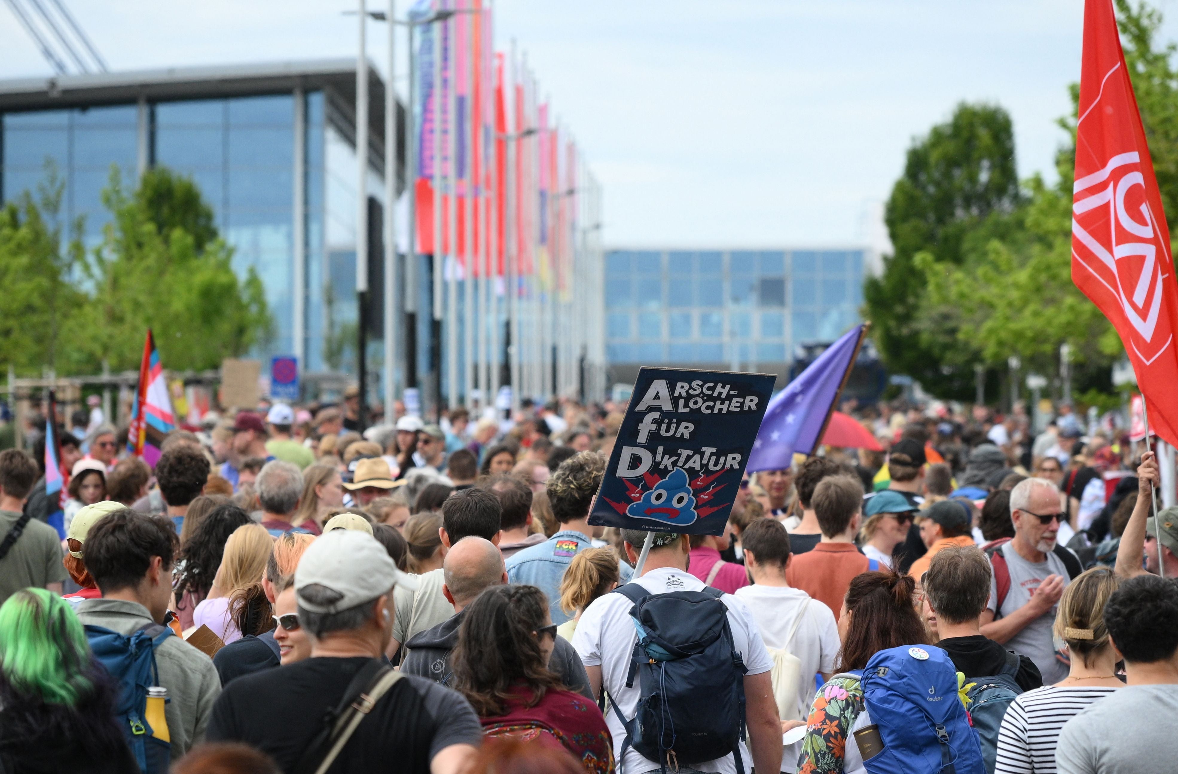 Viele Demonstrierende mit Schildern und Fahnen auf einer Protestkundgebung in einer Stadt.