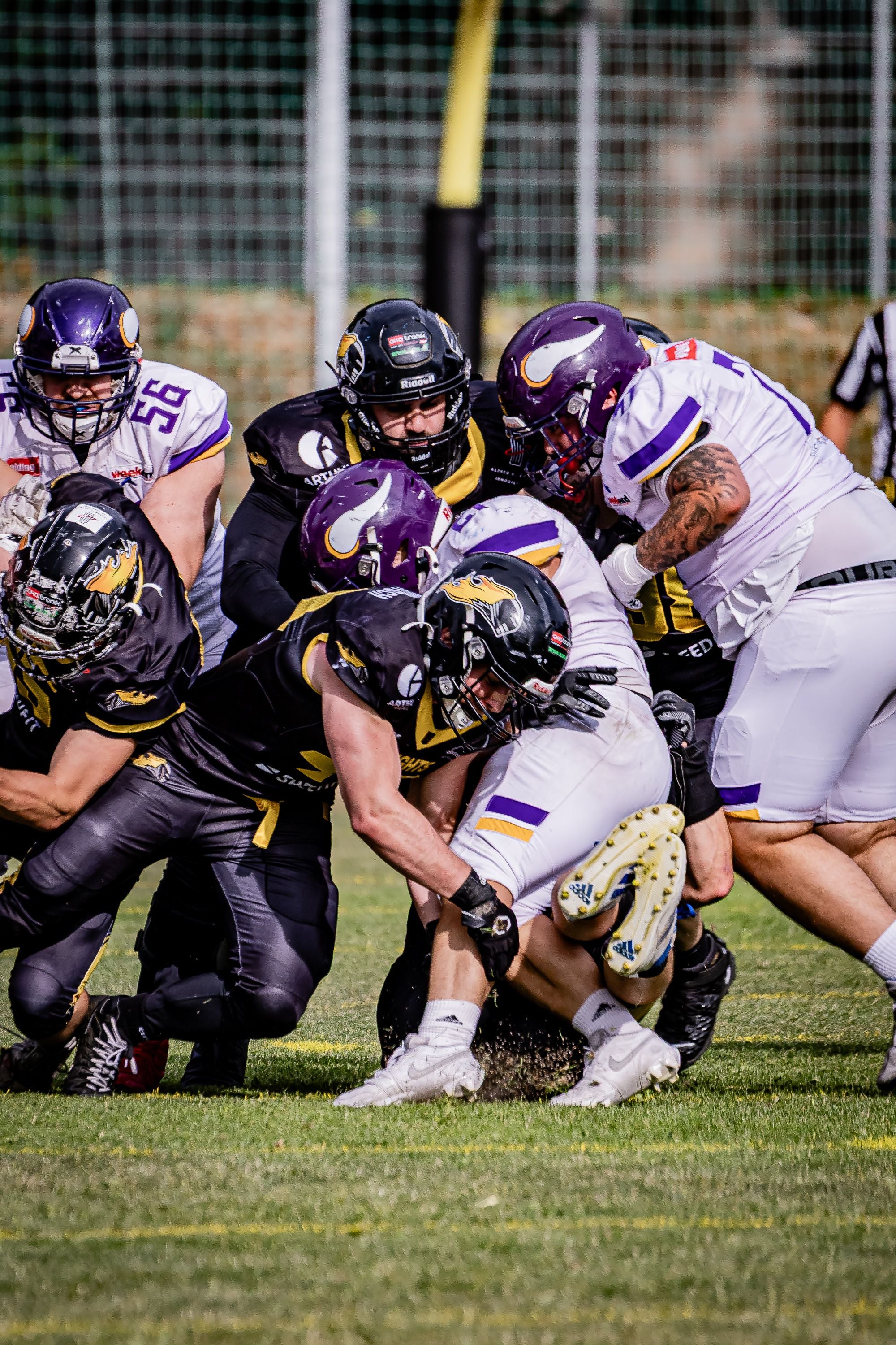 American Football-Spieler der Vikings und Knights kämpfen um den Ball auf dem Spielfeld.