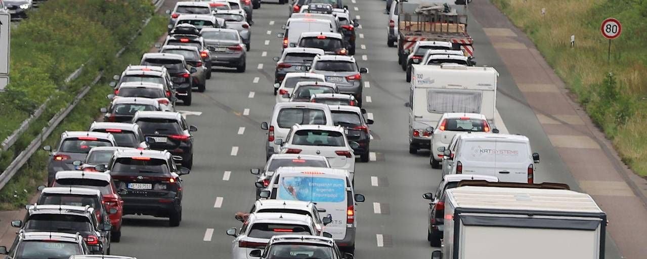 Autos stehen im Stau auf einer mehrspurigen Autobahn, Tempolimit 80 km/h ist sichtbar.