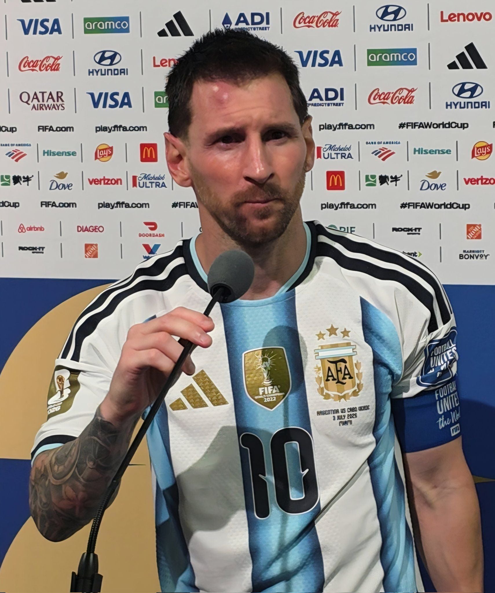 Ein Fußballspieler im argentinischen Trikot spricht in ein Mikrofon bei einer Pressekonferenz.