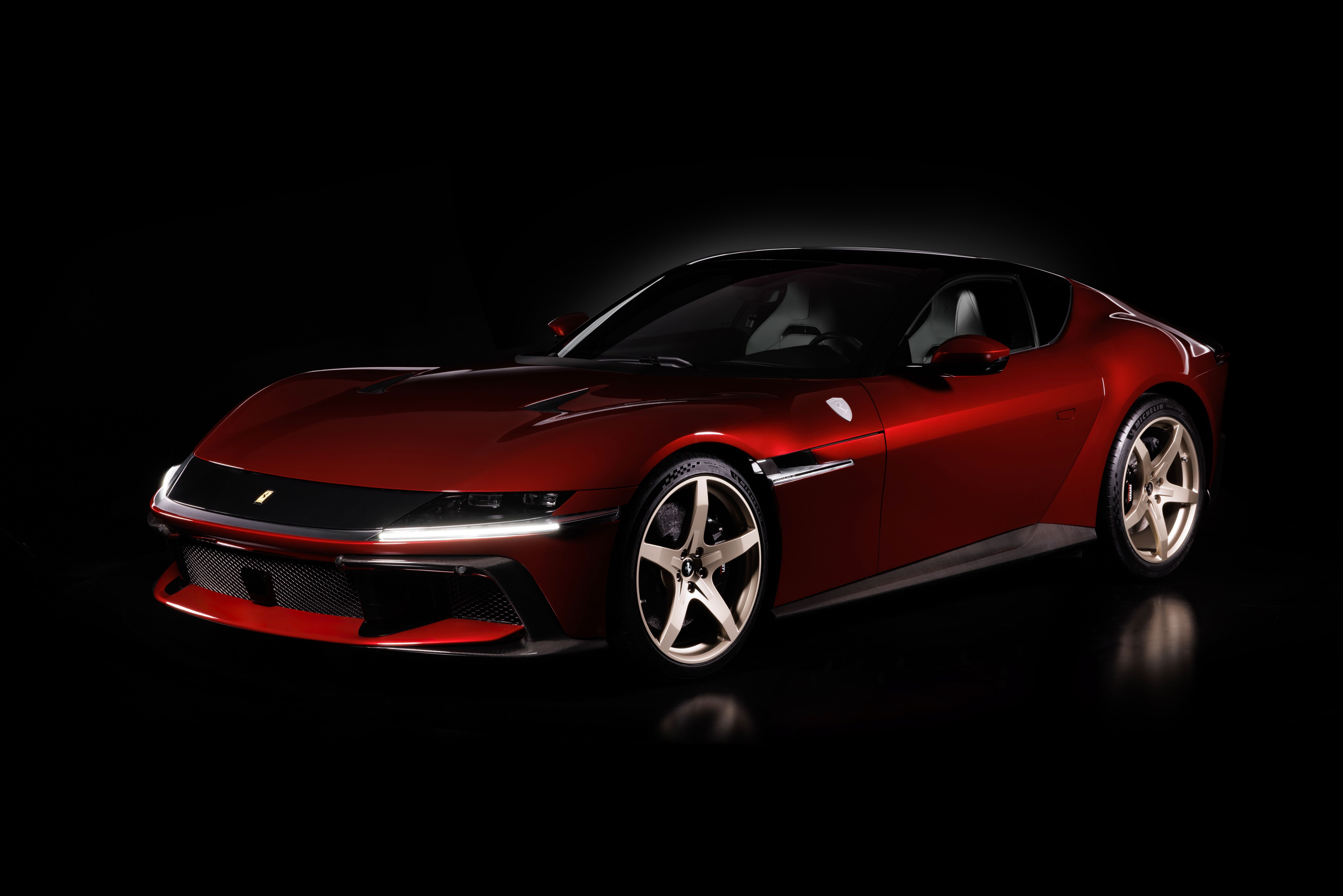 Roter Ferrari-Sportwagen vor schwarzem Hintergrund, seitlich von vorn fotografiert.