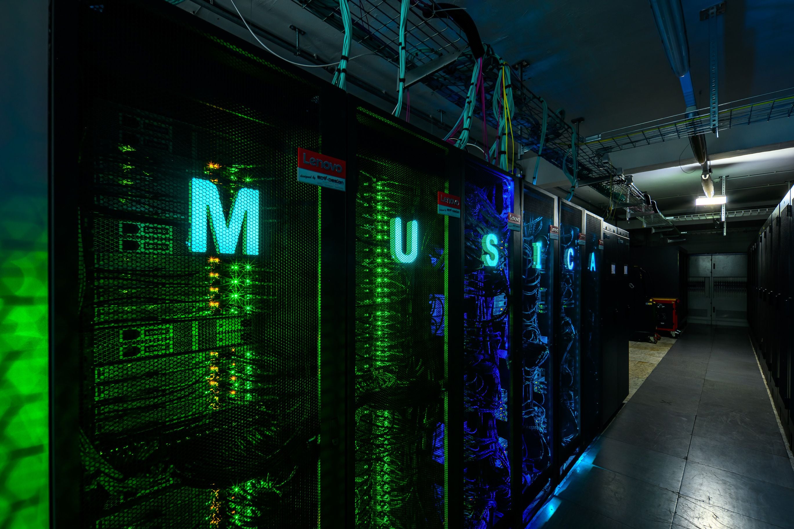 Serverraum mit beleuchteten Buchstaben "MUSICA" auf den Gehäusen eines Supercomputers.