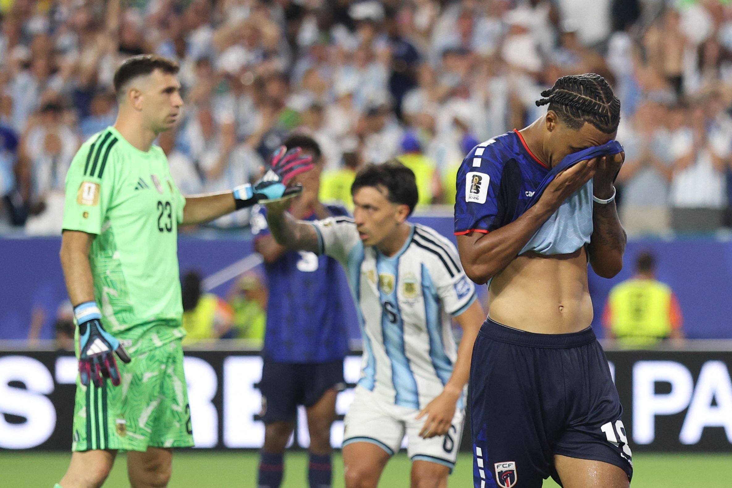 Ein Fußballspieler von Kap Verde ist enttäuscht, während argentinische Spieler im Hintergrund jubeln.