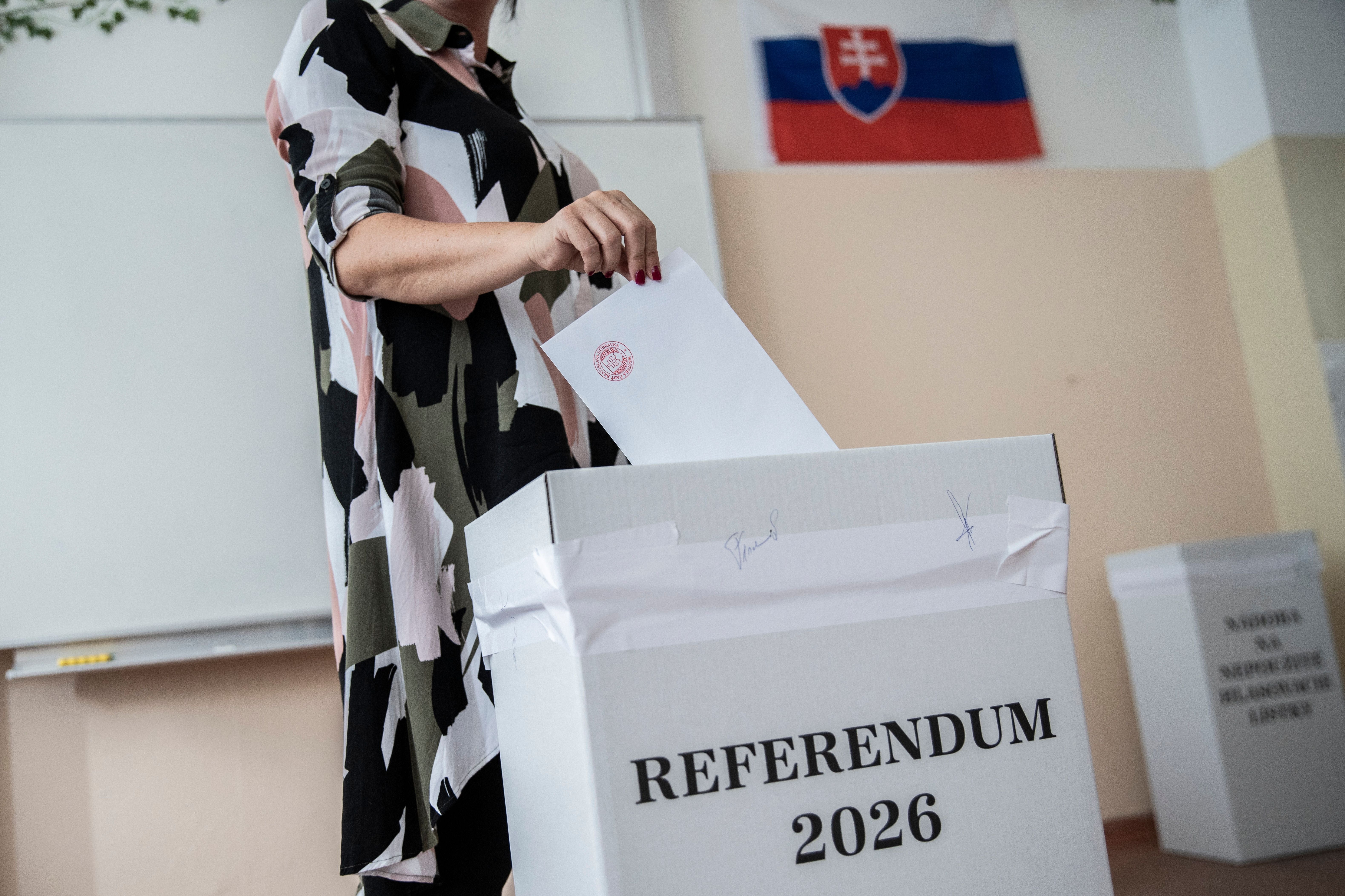 Eine Frau wirft bei einem Referendum 2026 in der Slowakei einen Wahlumschlag in eine Urne.