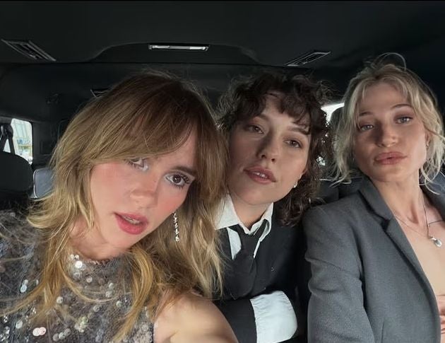 Drei junge Frauen machen ein Selfie in einem Auto, elegant gekleidet als Hochzeitsgäste.