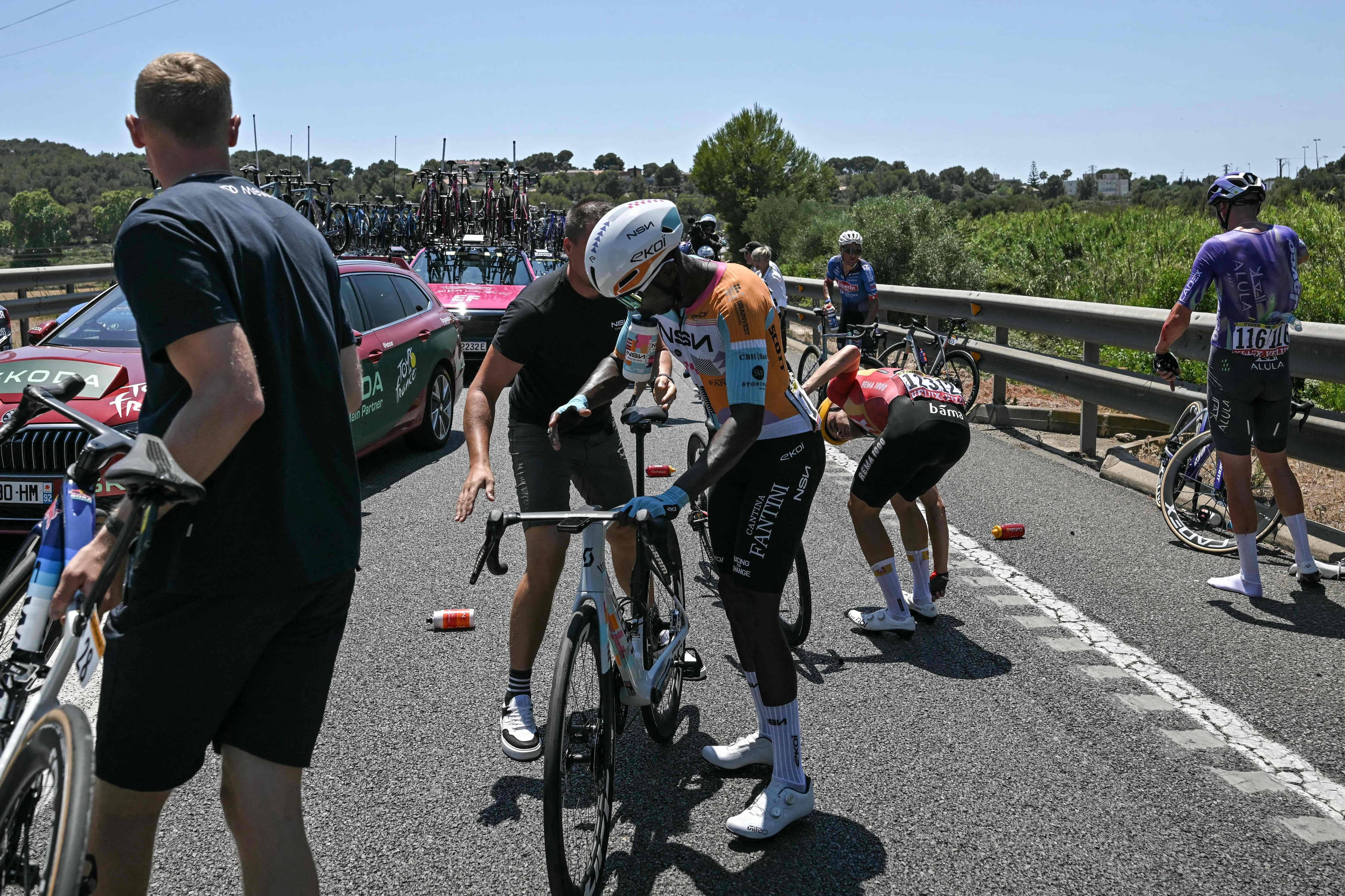 Radfahrer richten nach einem Sturz bei der Tour de France ihre Fahrräder auf der Straße her.