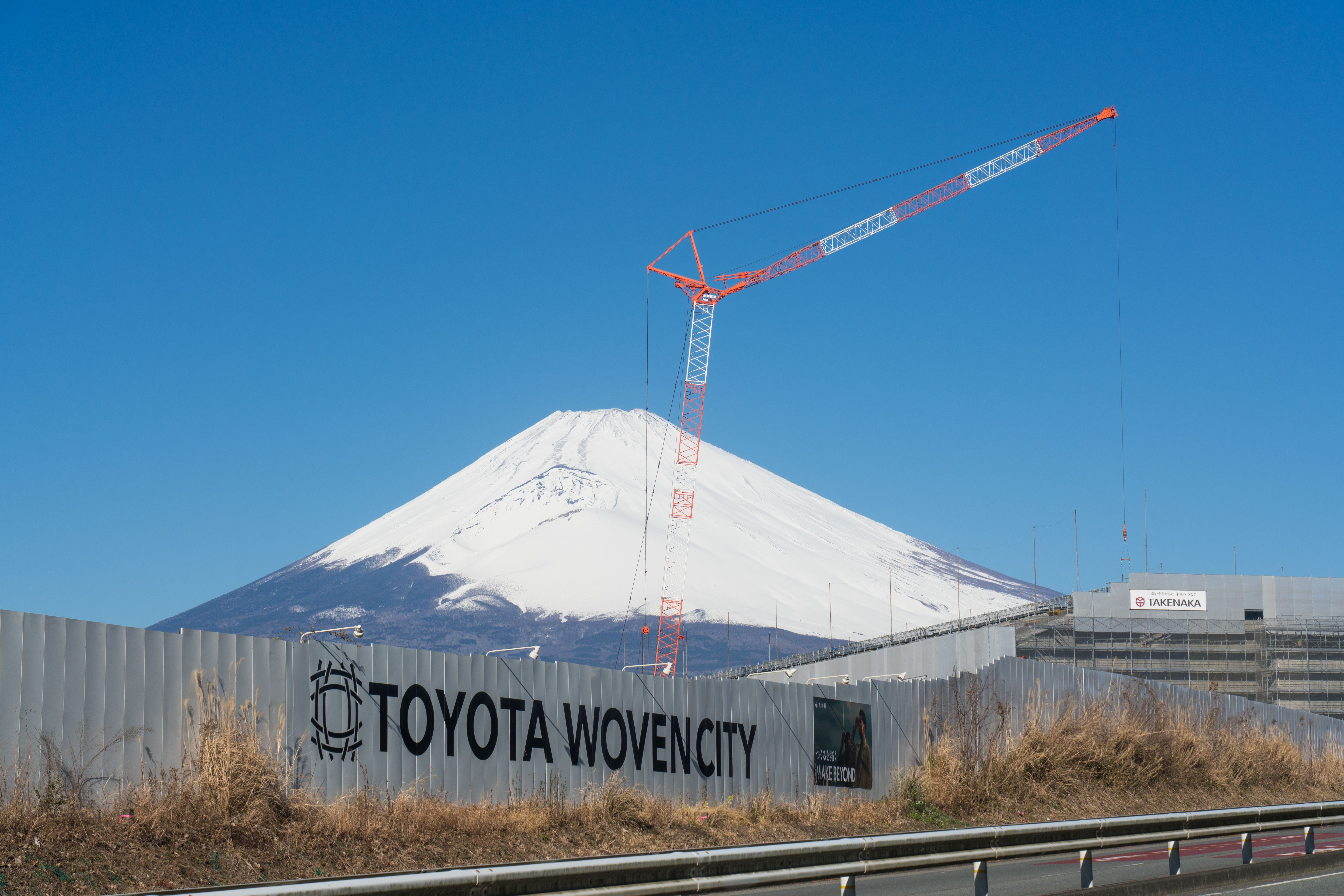 Bau der Toyota Woven City 2024 mit Kran, im Hintergrund schneebedeckter Berg Fuji.