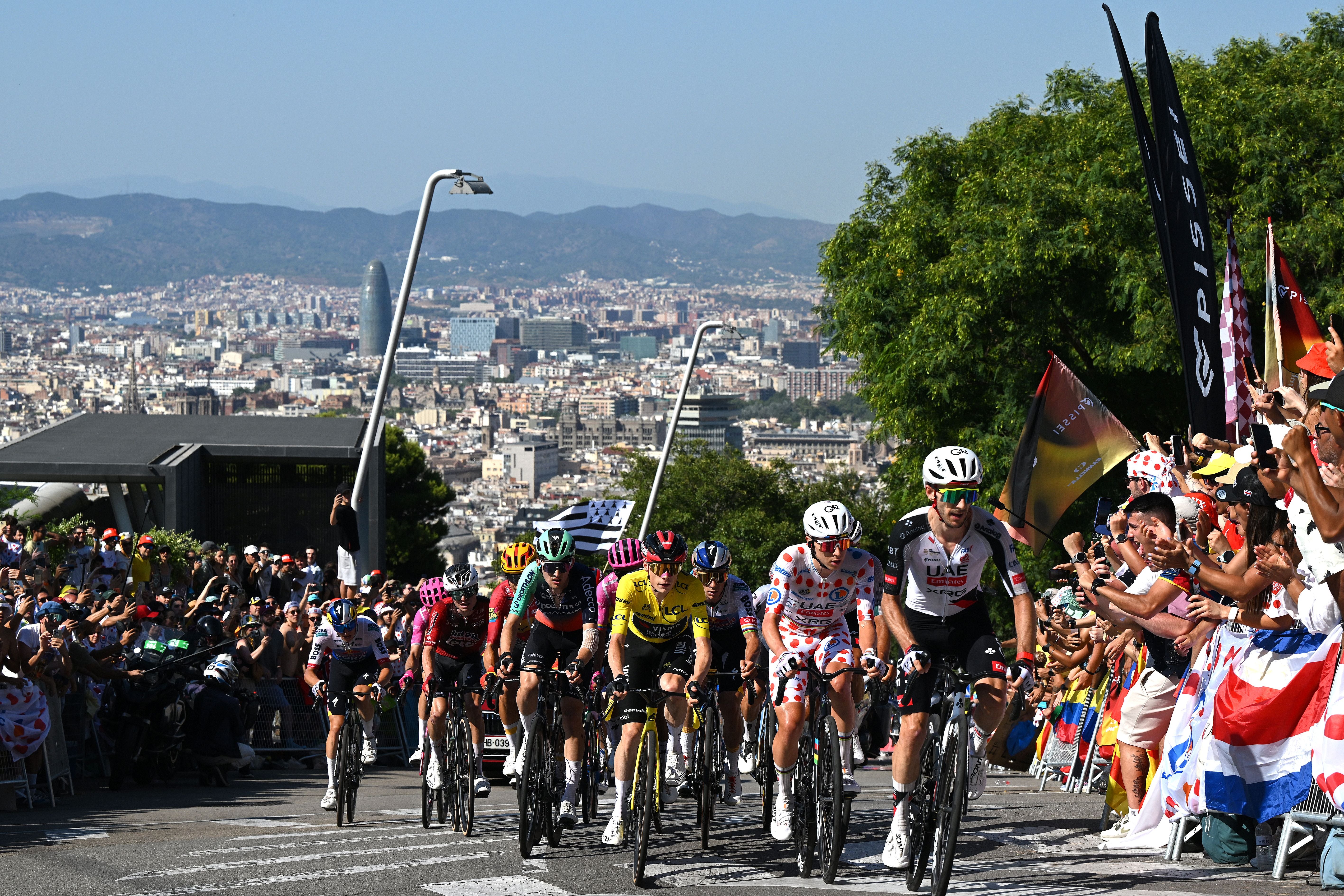 Radfahrer fahren bei der Tour de France 2026 durch Barcelona, jubelnde Zuschauer am Straßenrand.