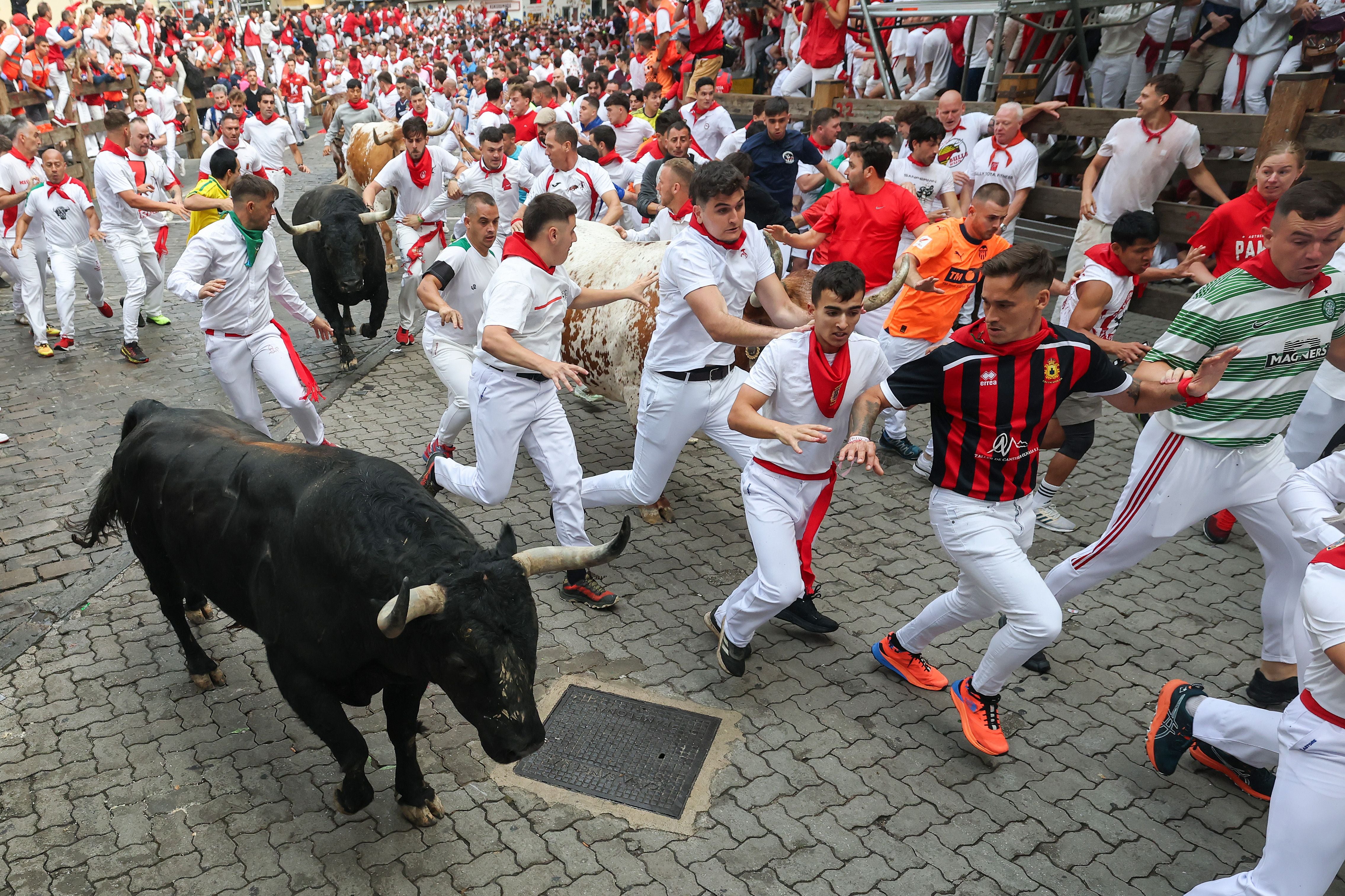 Menschen rennen vor mehreren Stieren während dem Stierrennen beim San Fermín Festival in Pamplona.