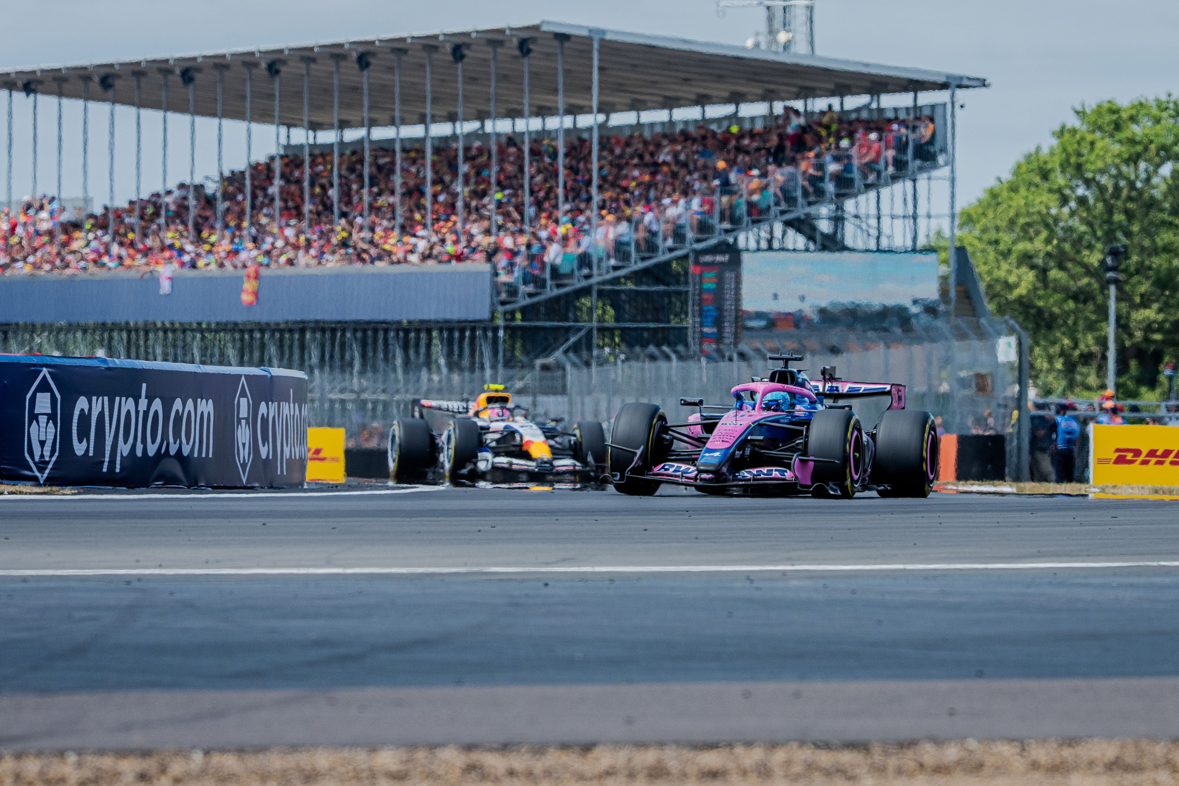 Zwei Formel-1-Autos fahren auf der Rennstrecke vor vollen Tribünen beim Silverstone Grand Prix.