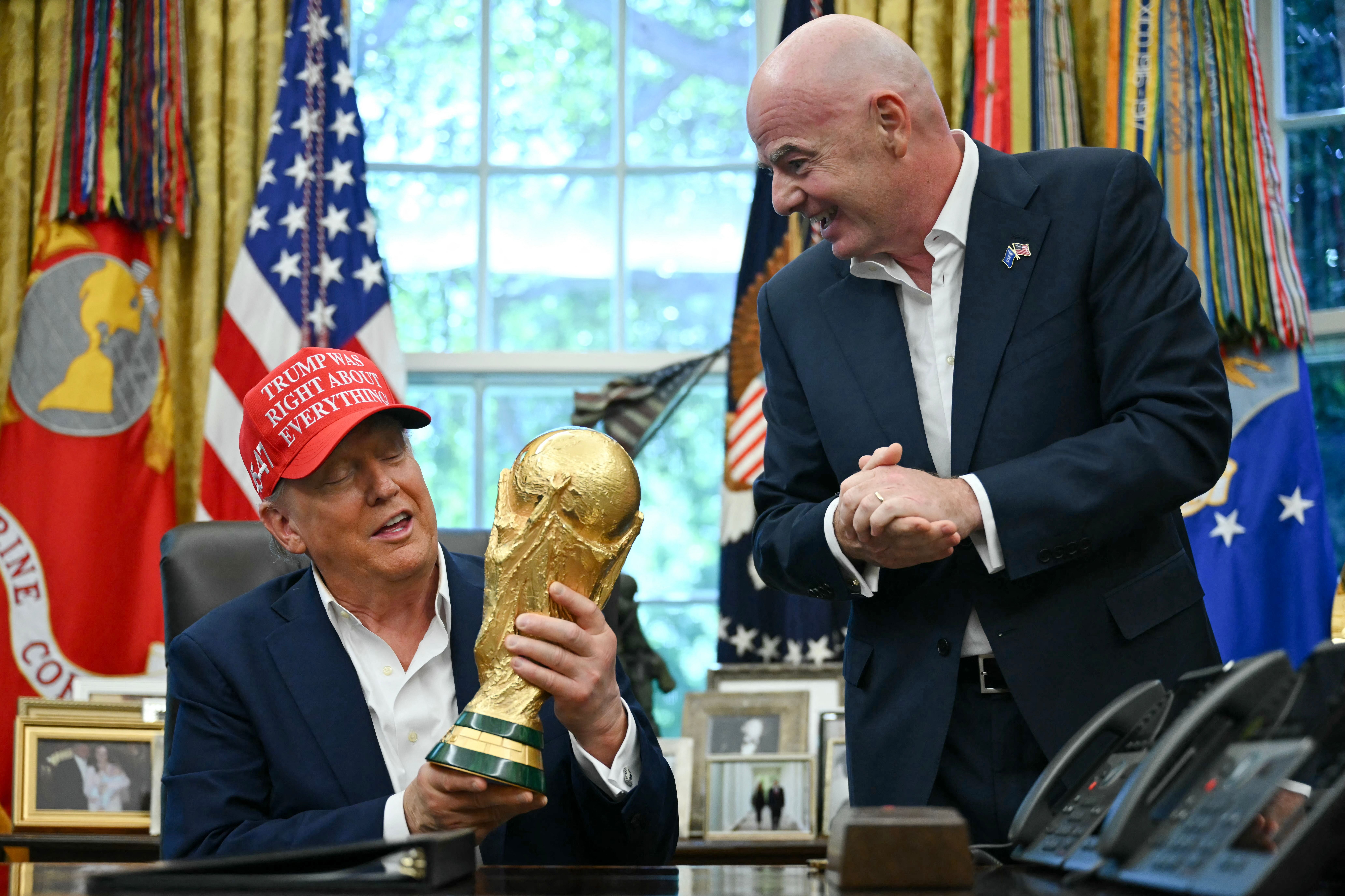 Donald Trump hält im Oval Office den WM-Pokal, neben ihm steht Gianni Infantino lächelnd.
