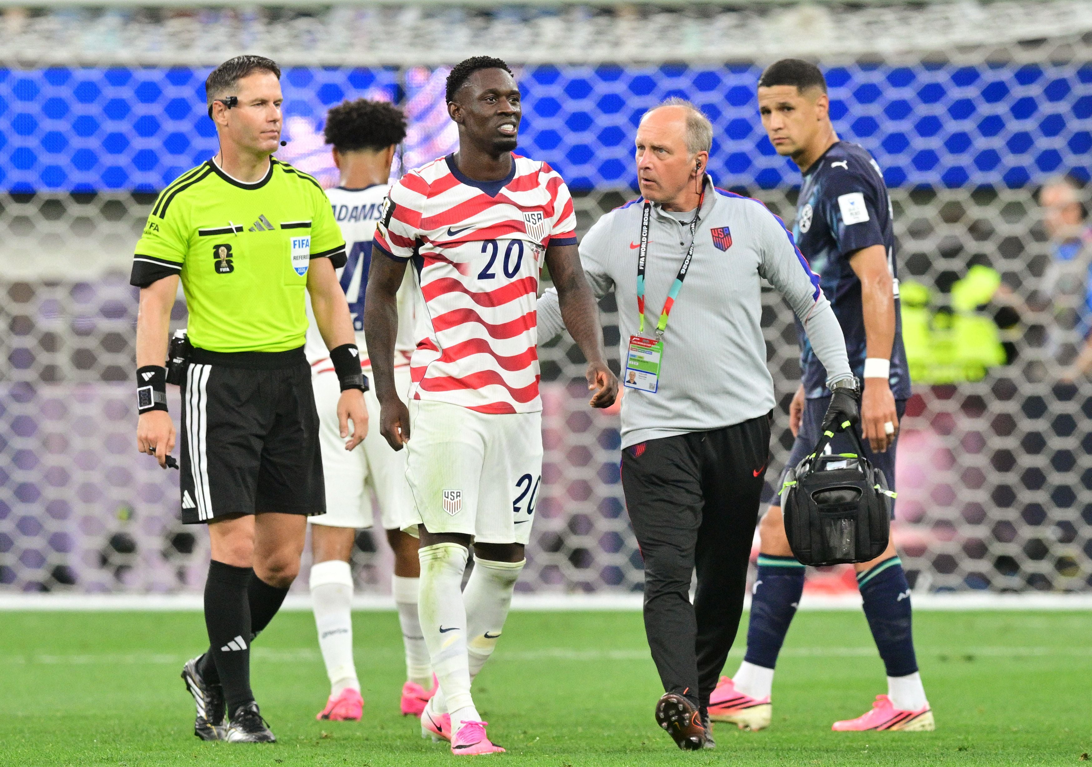 Ein US-Spieler verlässt mit Betreuern und Schiedsrichter während eines Fußballspiels den Platz.