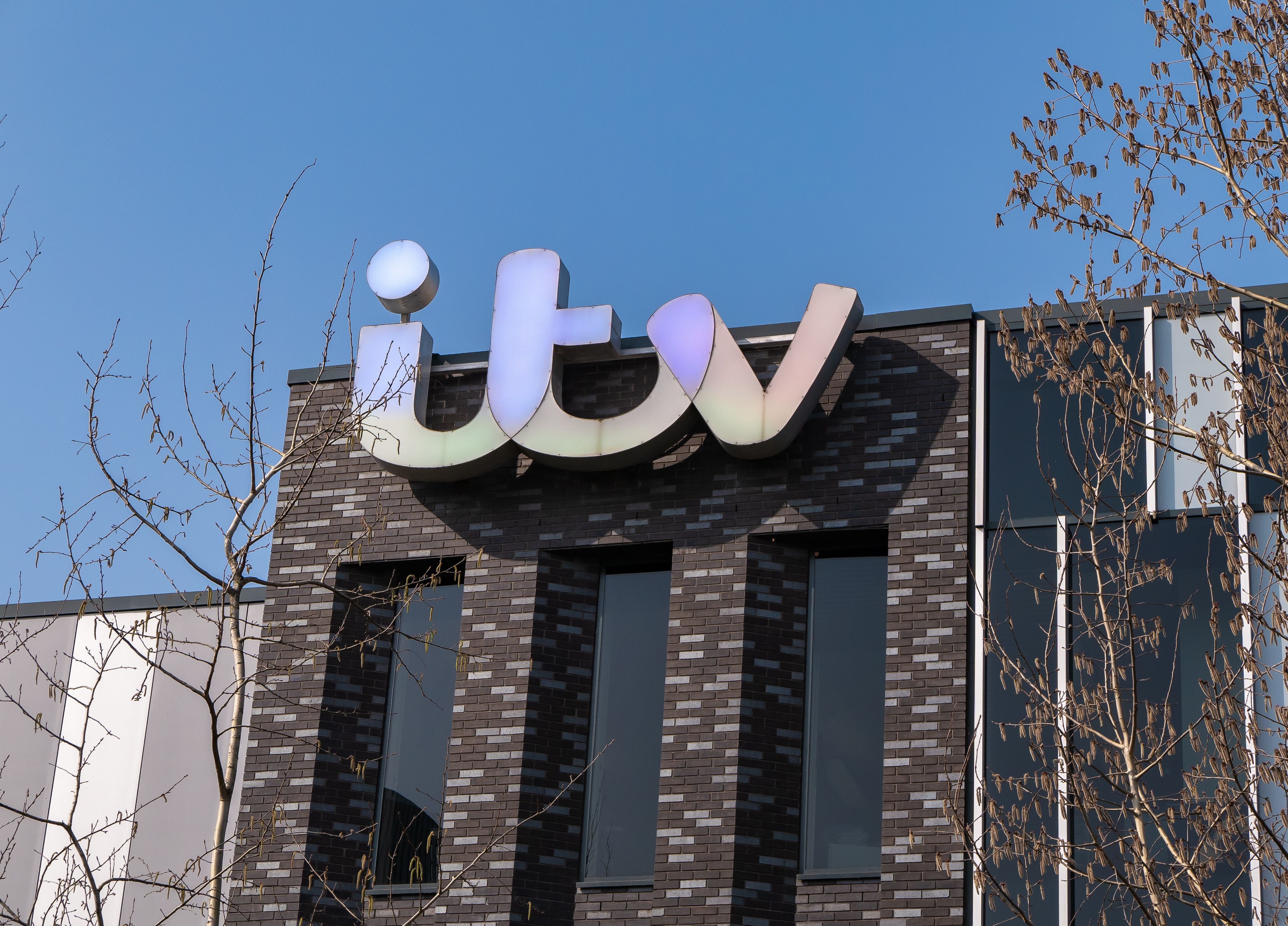 Das ITV-Logo auf einem modernen Gebäude in Media City, Salford, Manchester bei blauem Himmel.