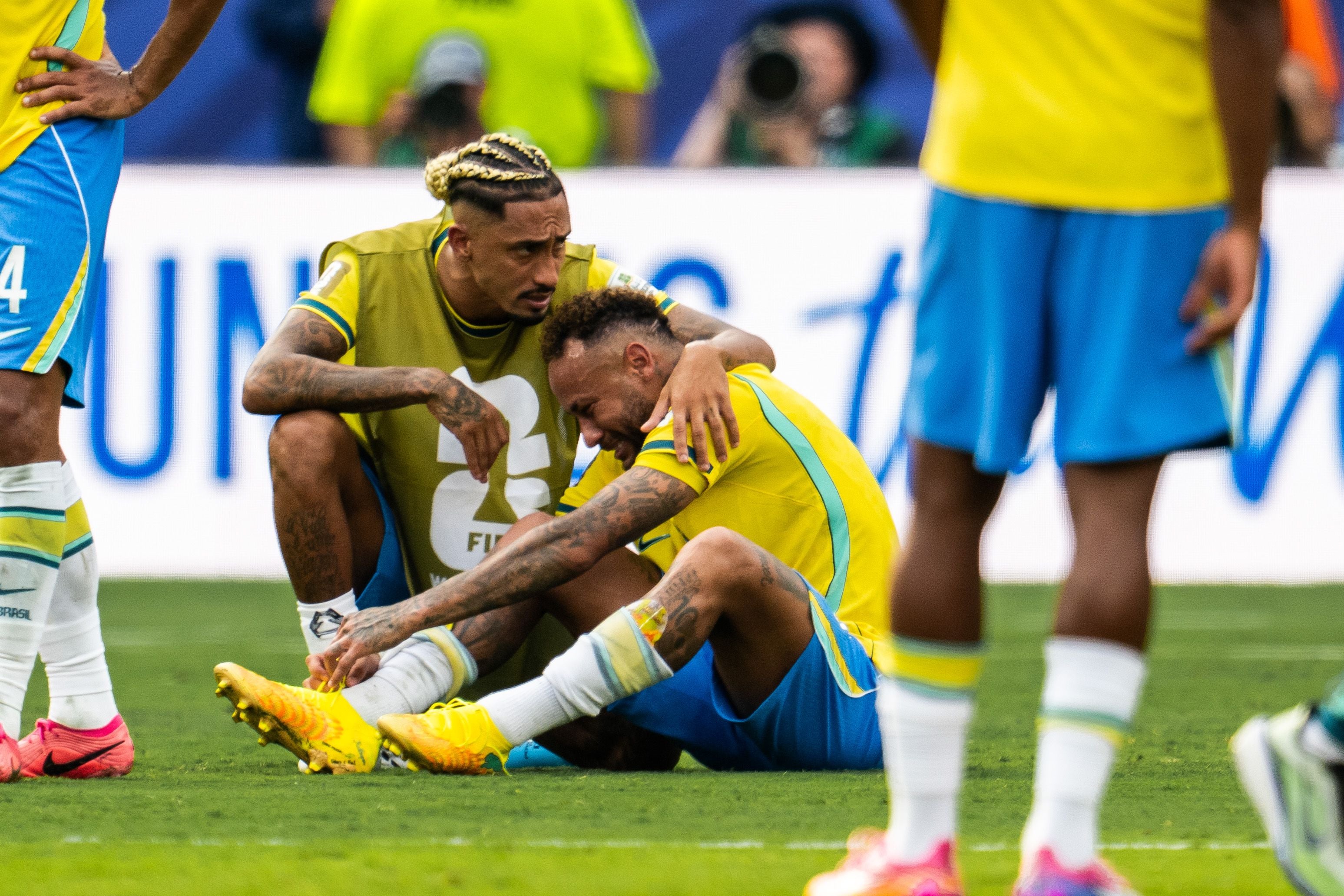 Ein brasilianischer Fußballspieler tröstet den am Boden sitzenden, enttäuschten Neymar Jr.