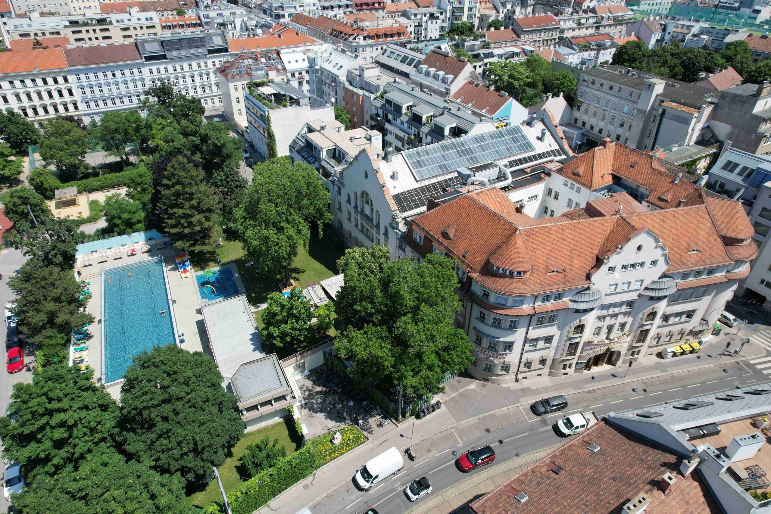 Luftaufnahme des Jörgerbads mit Schwimmbecken, Garten und umgebenden Gebäuden in Wien.
