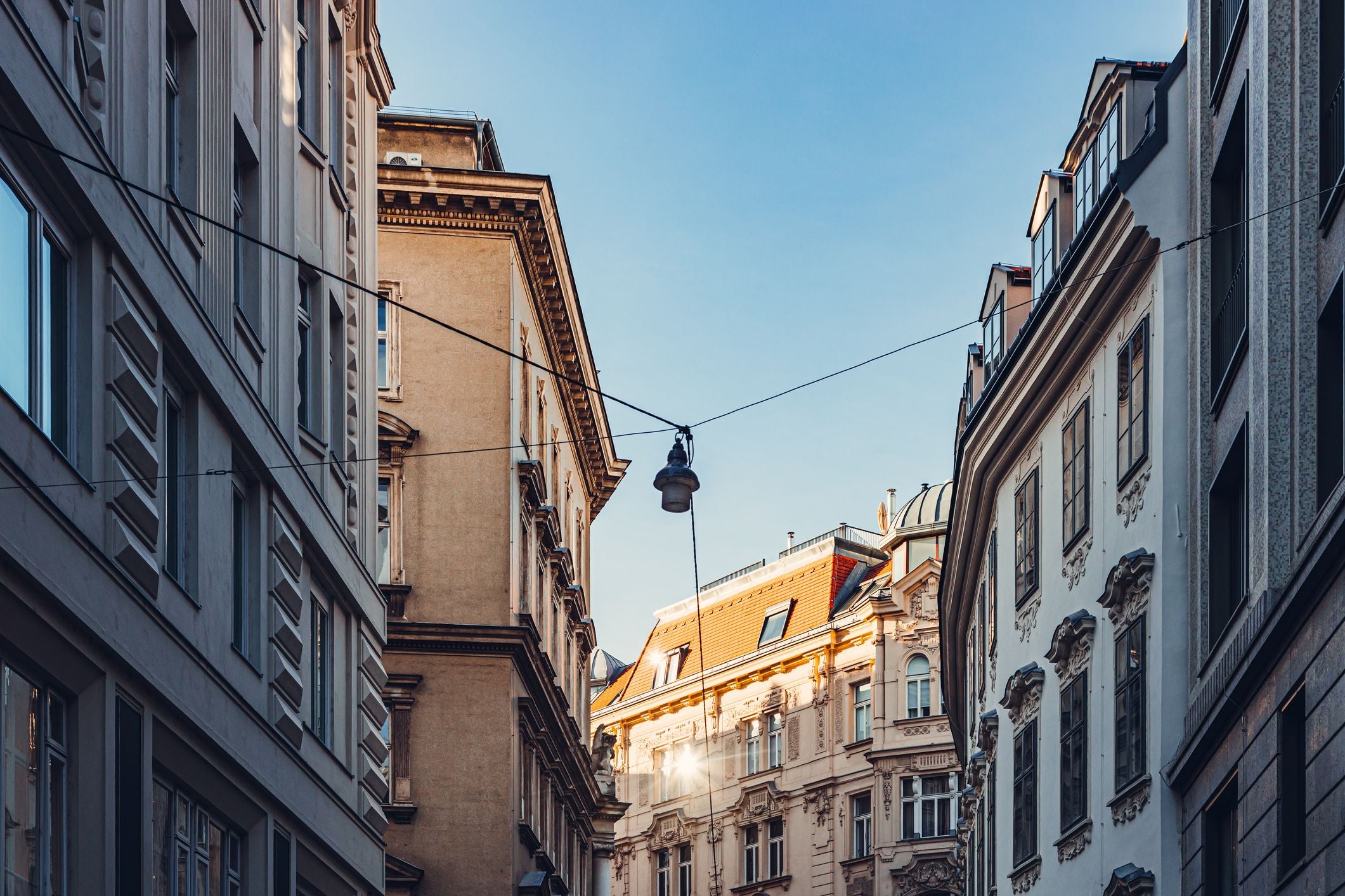 Altbauten in einer engen Wiener Straße bei Tageslicht mit blauem Himmel.