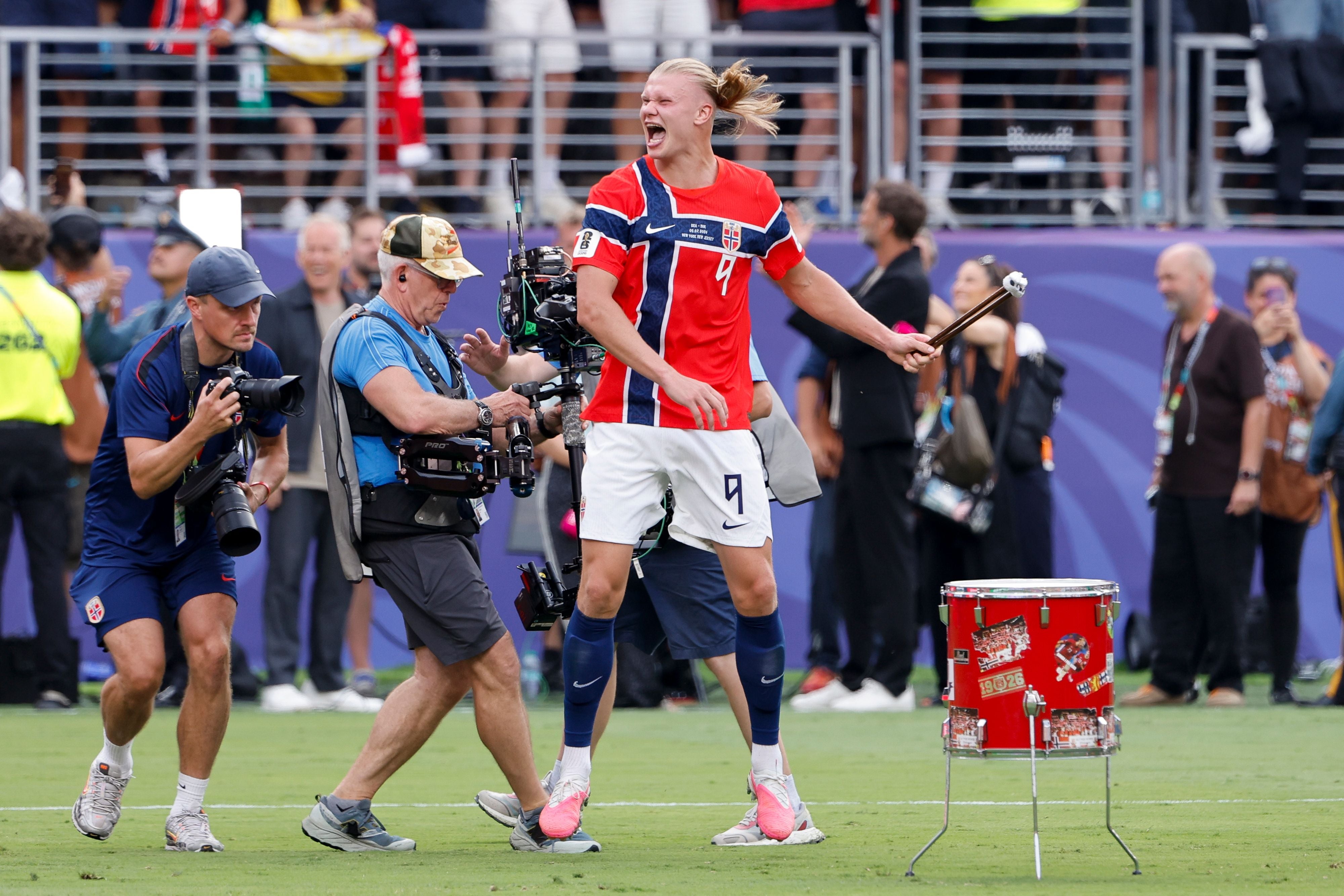 Ein norwegischer Fußballspieler trommelt jubelnd auf einer roten Trommel auf dem Spielfeld.
