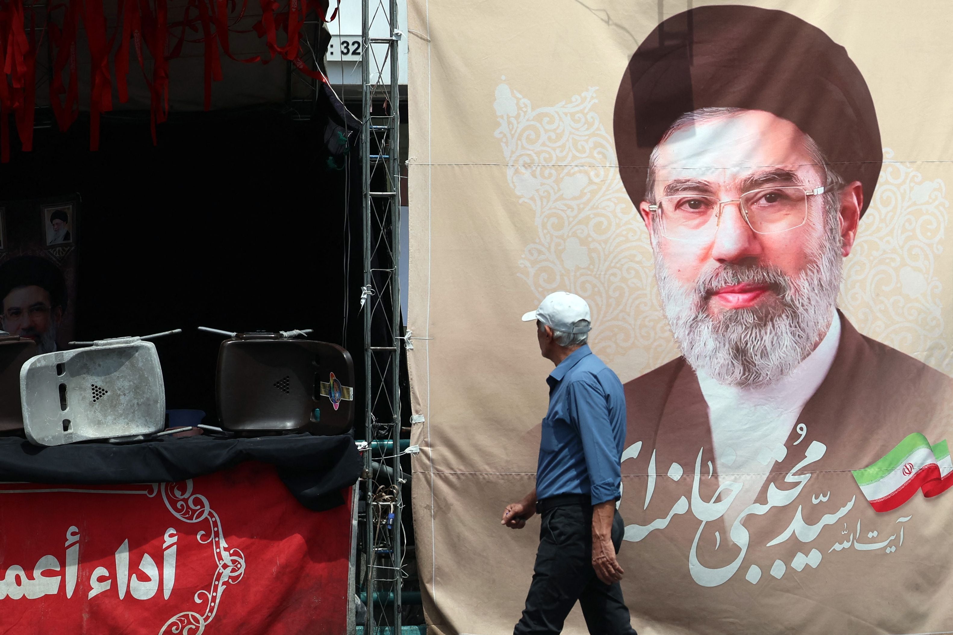 Ein Mann geht an einem großen Plakat mit dem Porträt von Mojtaba Khamenei in Teheran vorbei.