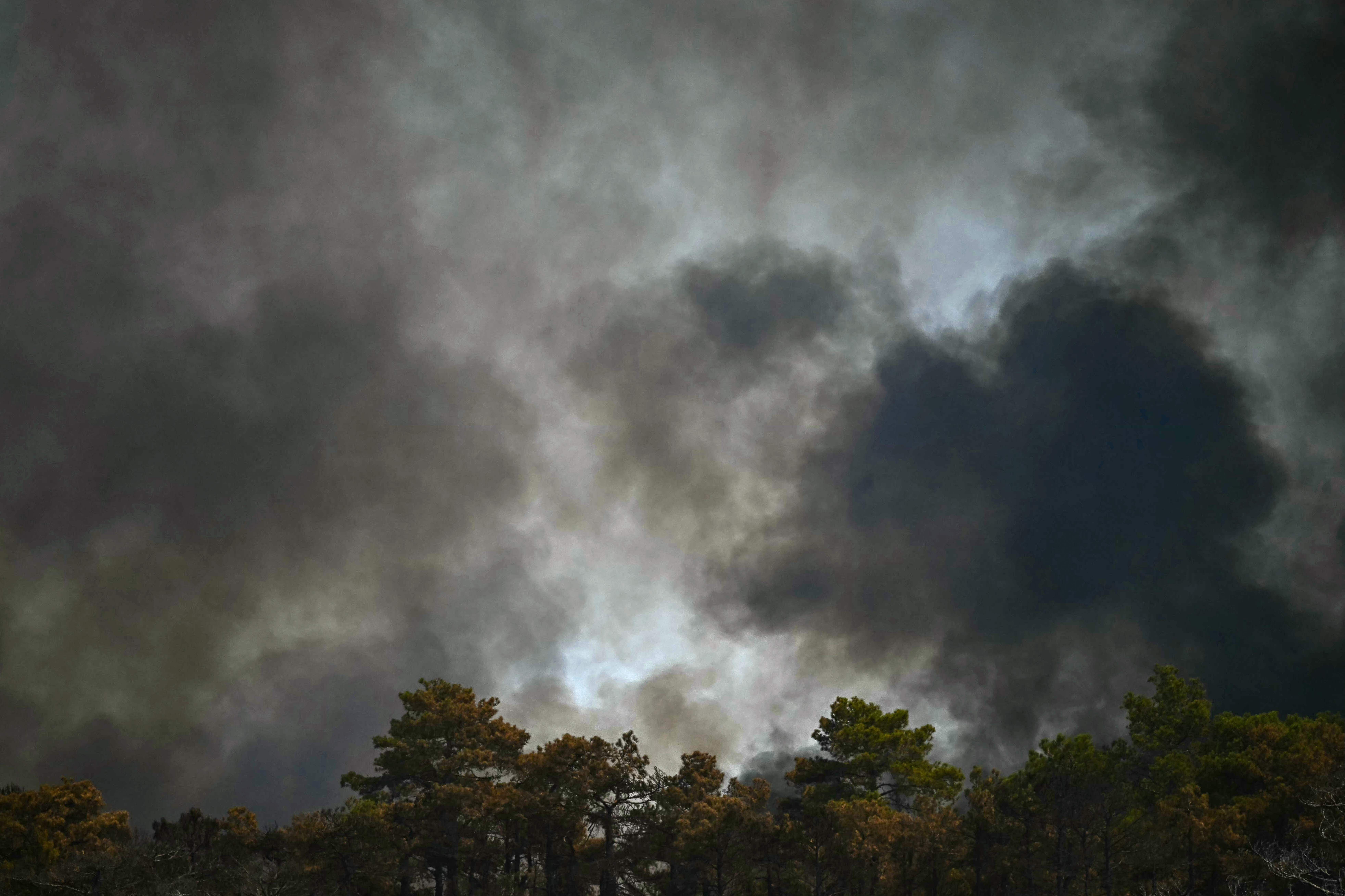 Smoke obscures the sky as a wildfire rages in the southern France department of Herault as 700 hundred firefighters backed by special aircraft battled to control a 'gigantic' blaze in nearby department of Pyrenees-Orientales, near the town of Carlencas-et-Levas on July 6, 2026. Wildfires raged across southern Europe, forcing thousands of people to evacuate their homes and prompting officials to ban spectators from a stage of the storied Tour de France cycling race. (Photo by Gabriel BOUYS / AFP)