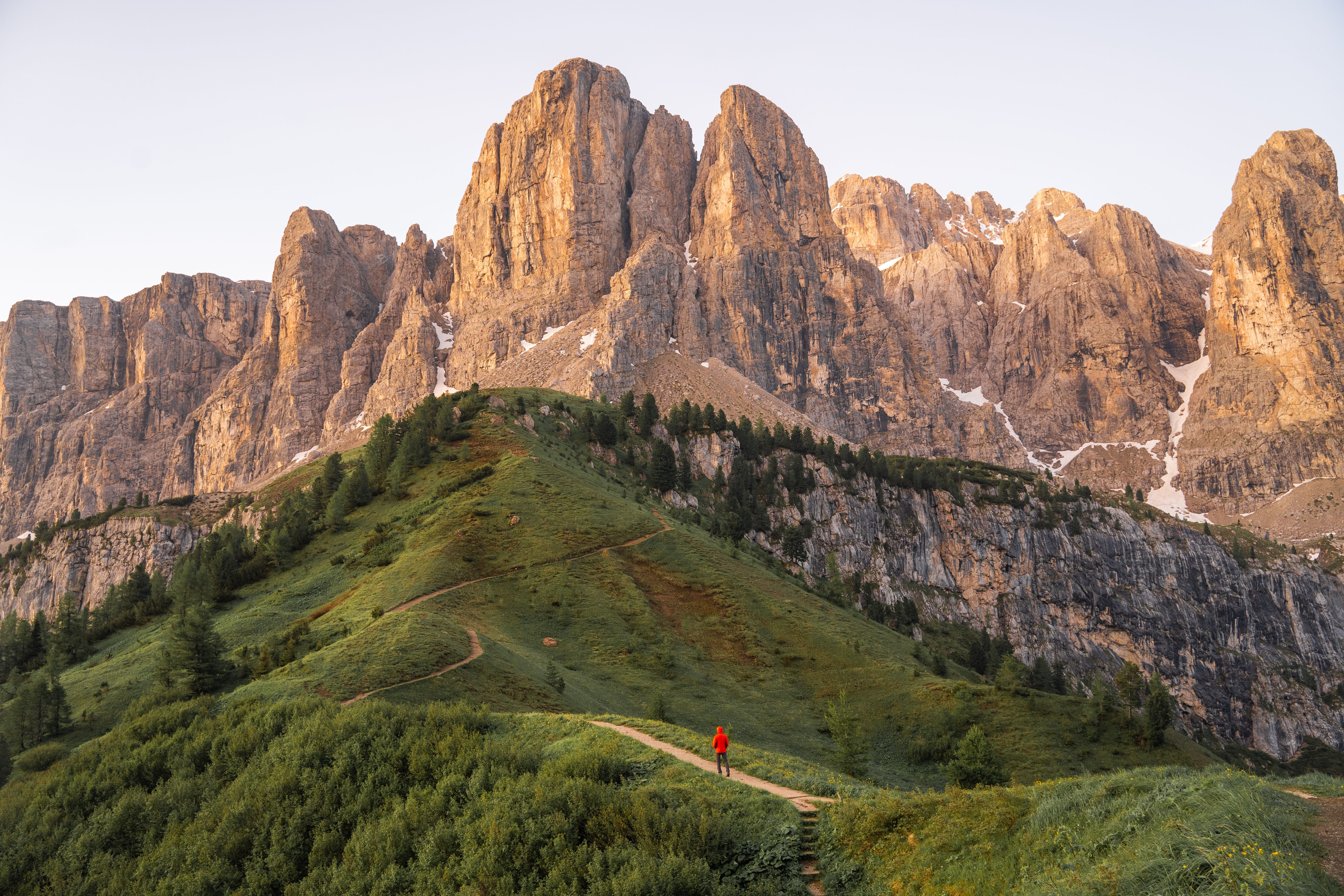 Wanderer im roten Jacke am Gardena-Pass vor den Dolomiten bei Sonnenaufgang.