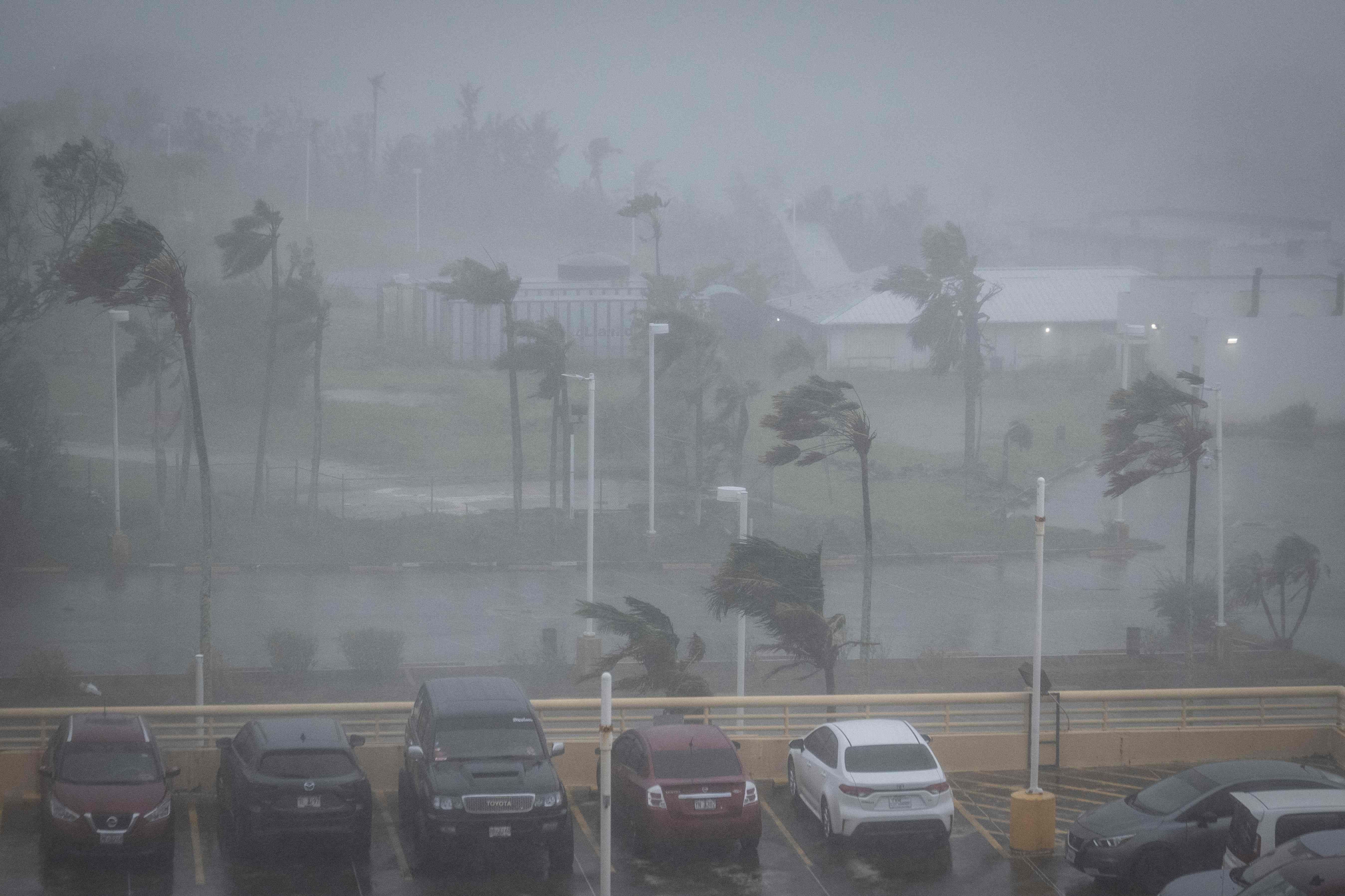 Starker Wind biegt Palmen und erschwert die Sicht auf einem Parkplatz während eines Taifuns in Guam.