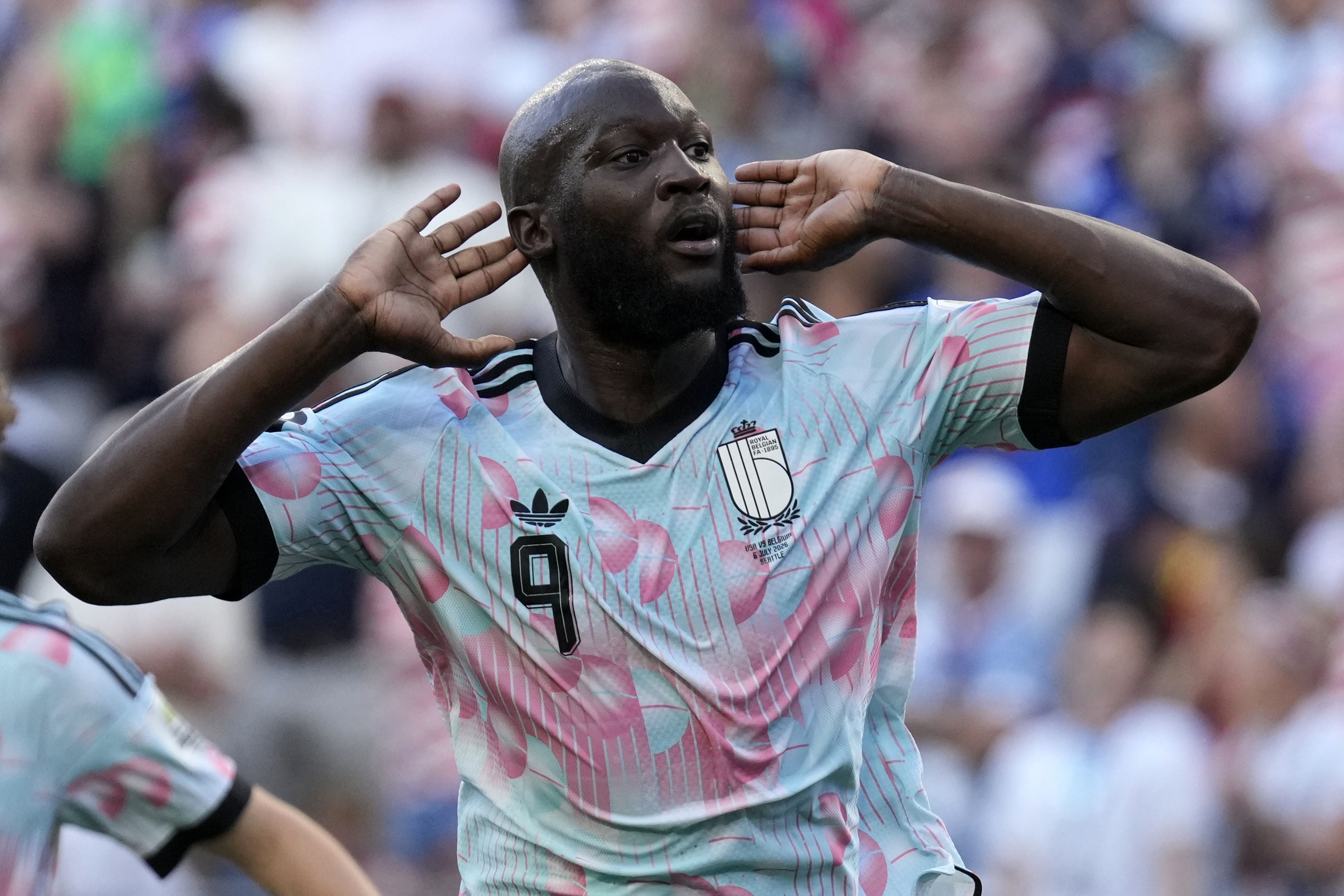 Belgischer Fußballspieler jubelt mit den Händen an den Ohren im Trikot während eines Spiels.