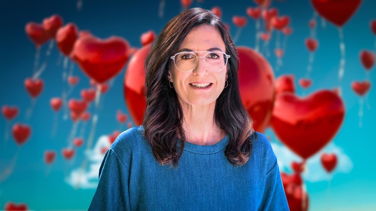 Frau mit Brille vor Hintergrund mit vielen roten Herz-Luftballons.