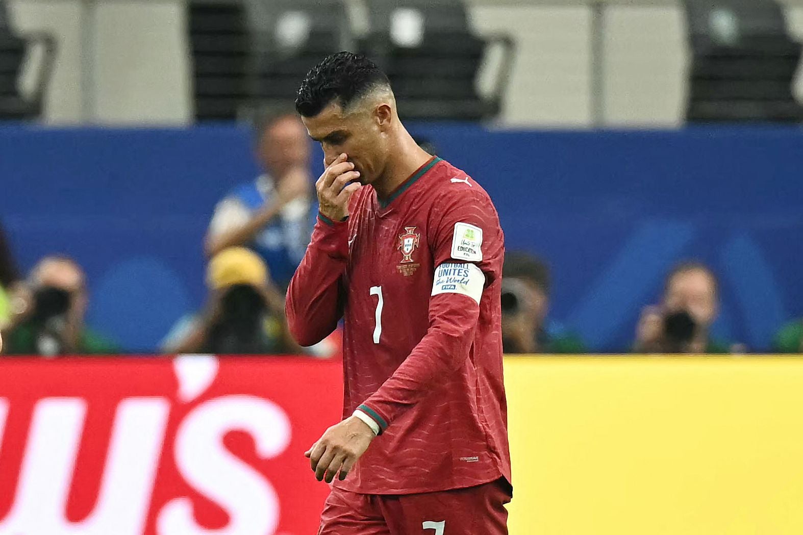 Ein enttäuschter portugiesischer Fußballspieler im roten Trikot verlässt das Spielfeld.