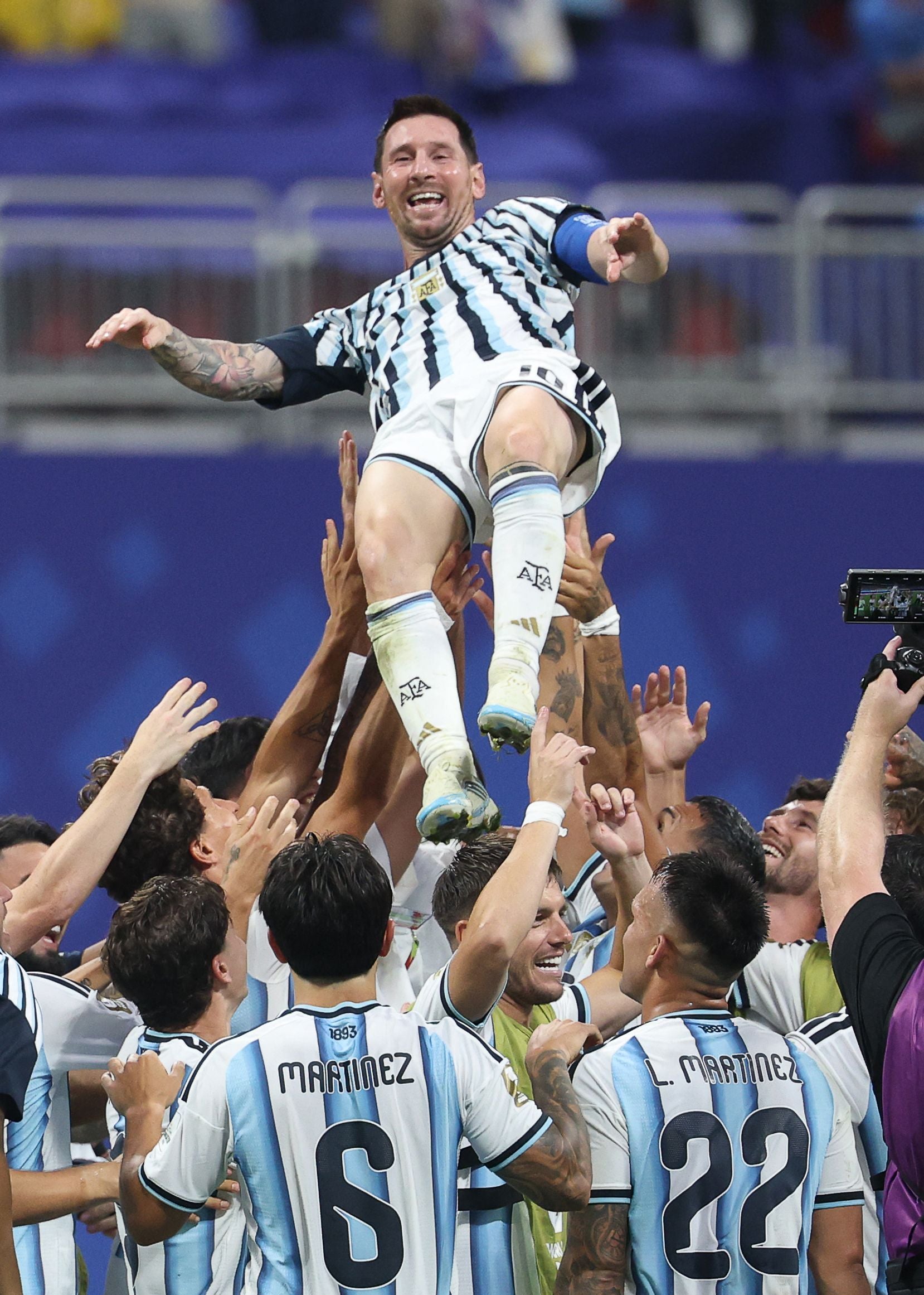Argentinische Fußballspieler heben jubelnd einen Mitspieler nach einem Sieg in die Luft.