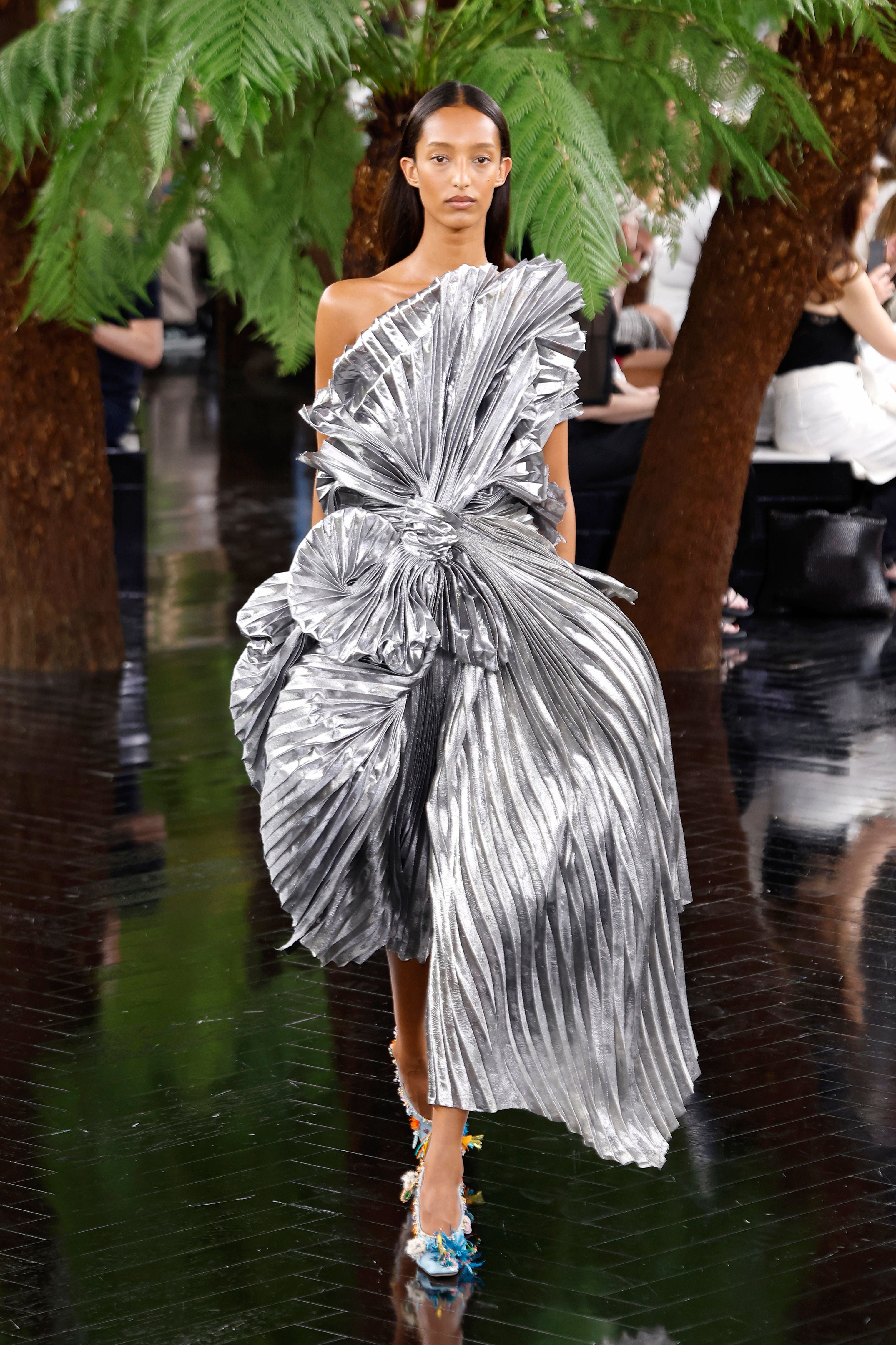 Model trägt silbernes, plissiertes Kleid mit strukturierten Details auf dem Laufsteg bei Dior in Paris.