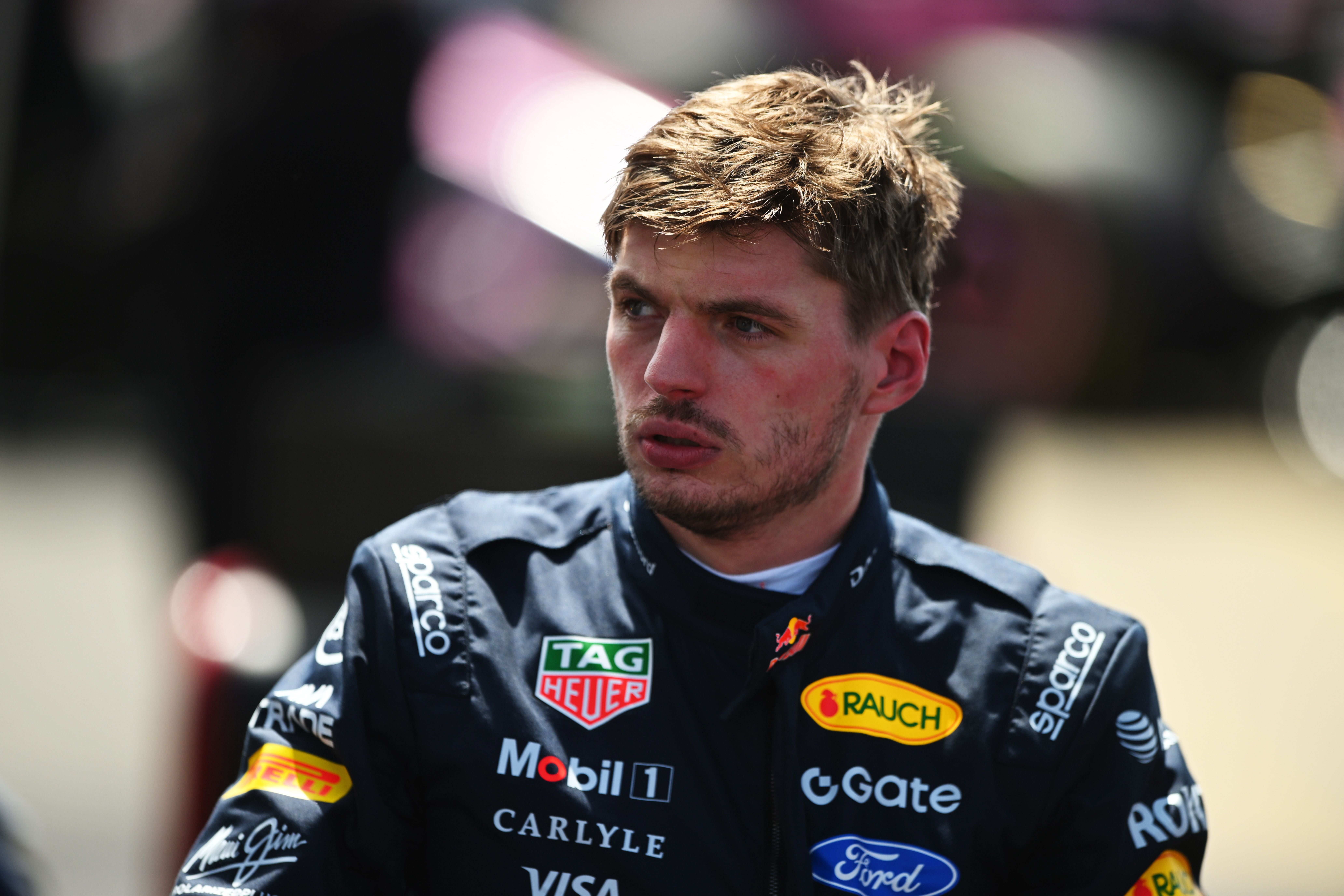 Ein Rennfahrer im Red Bull Racing Overall schaut konzentriert nach rechts, unscharfer Hintergrund.