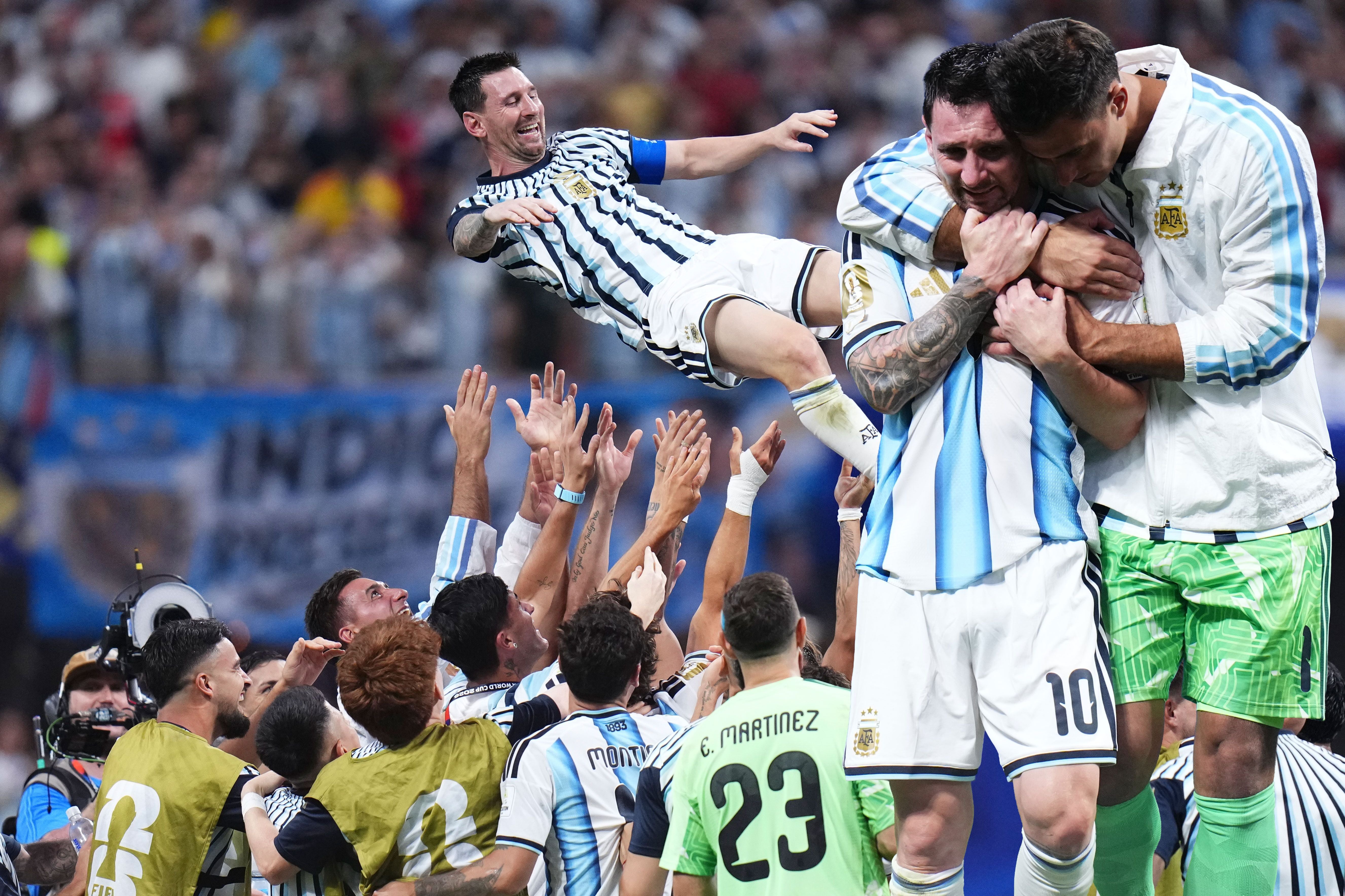 Argentinische Fußballspieler feiern auf dem Spielfeld, einer wird jubelnd in die Luft geworfen.